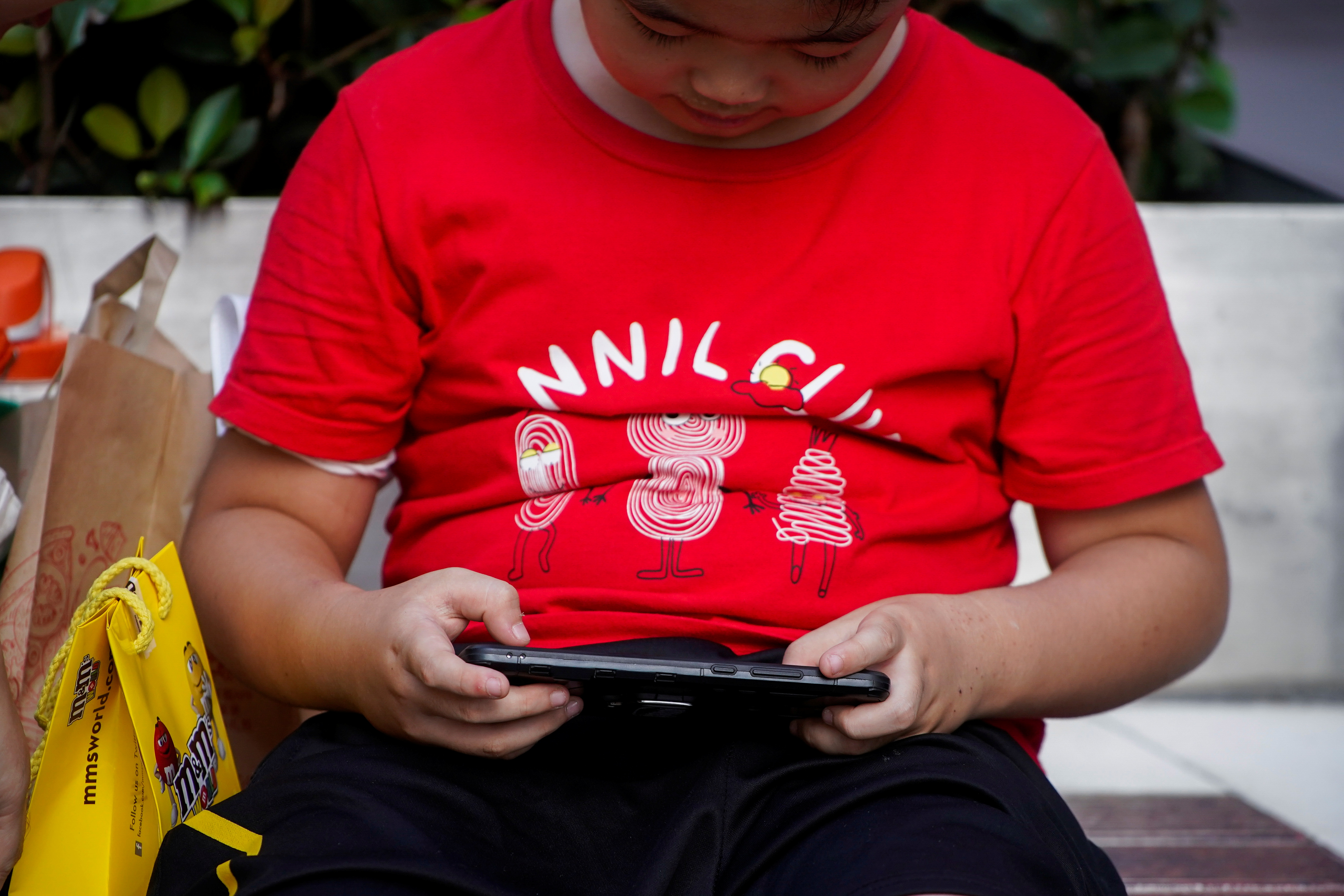 A boy plays a game on a phone on a street in Shanghai, China August 31, 2021. REUTERS/Aly Song