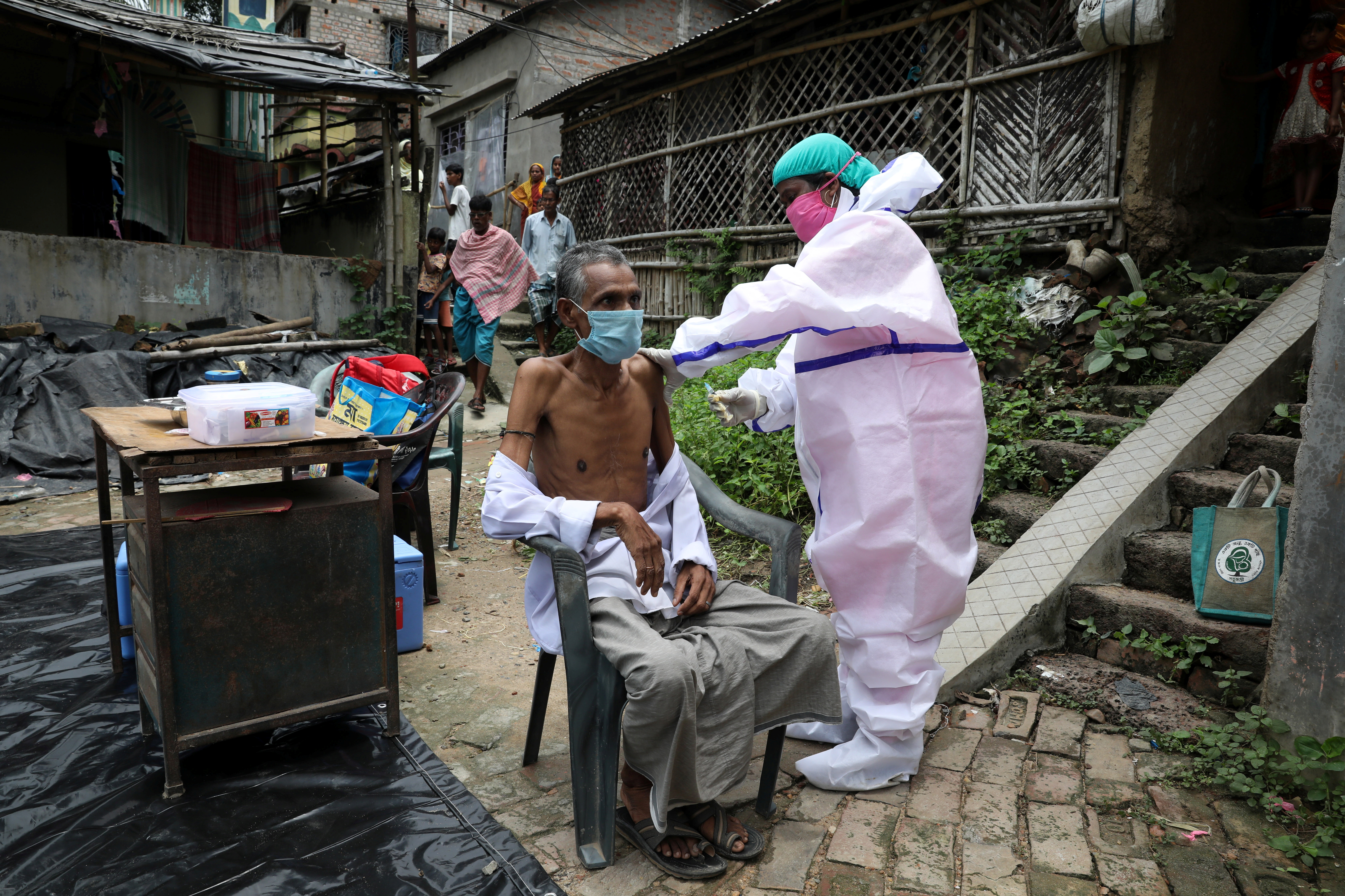 A villager receives a dose of COVISHIELD vaccine during a door-to-door vaccination and testing drive at Uttar Batora Island