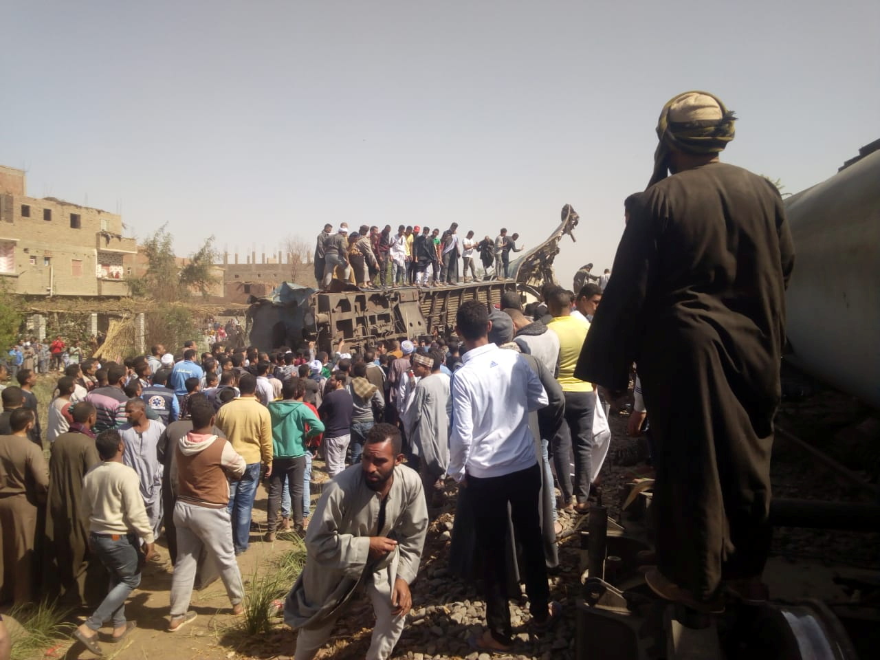 People inspect the damage after two trains have collided near the city of Sohag