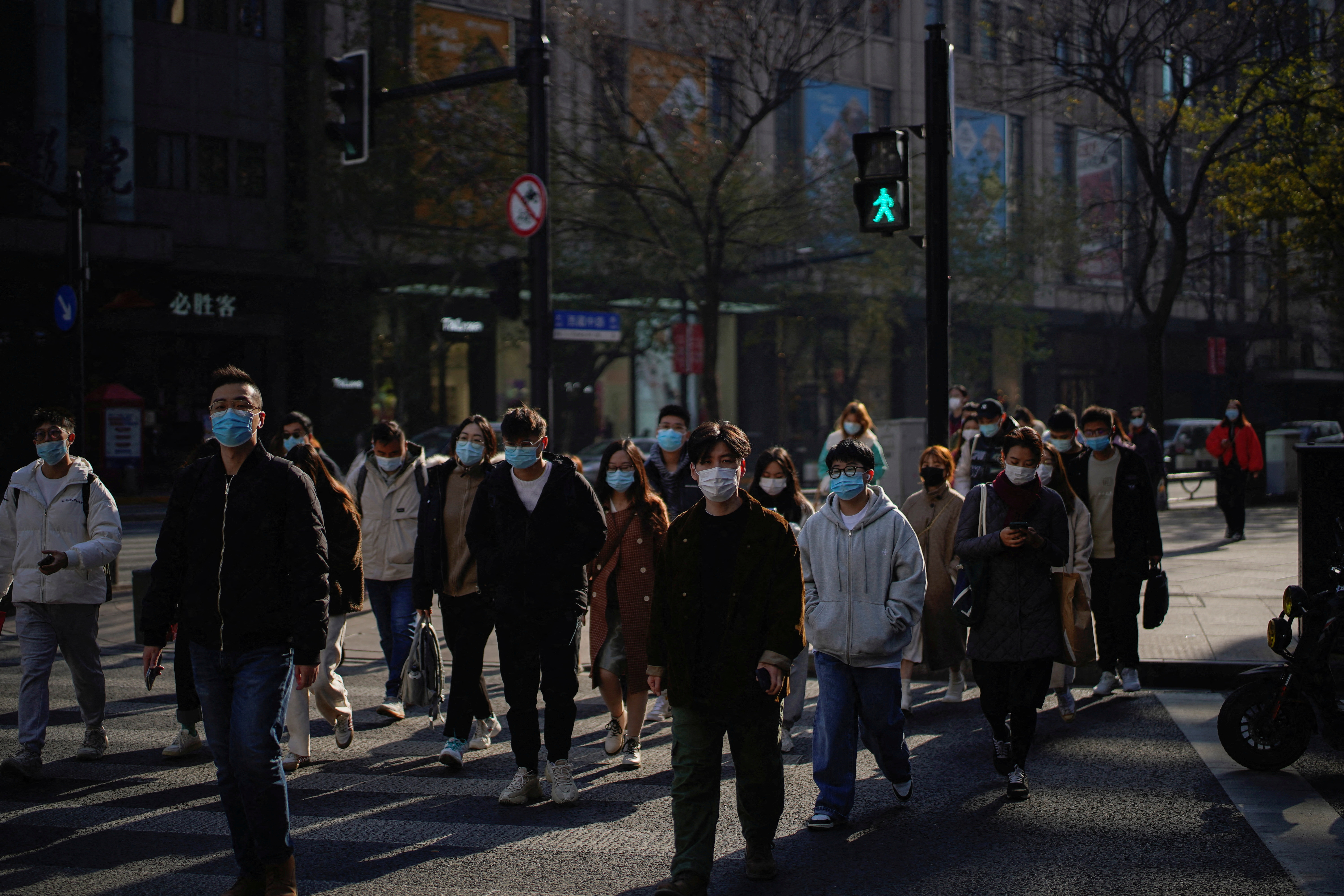 People wearing protective masks walk on a street, following new cases of the coronavirus disease (COVID-19), in Shanghai