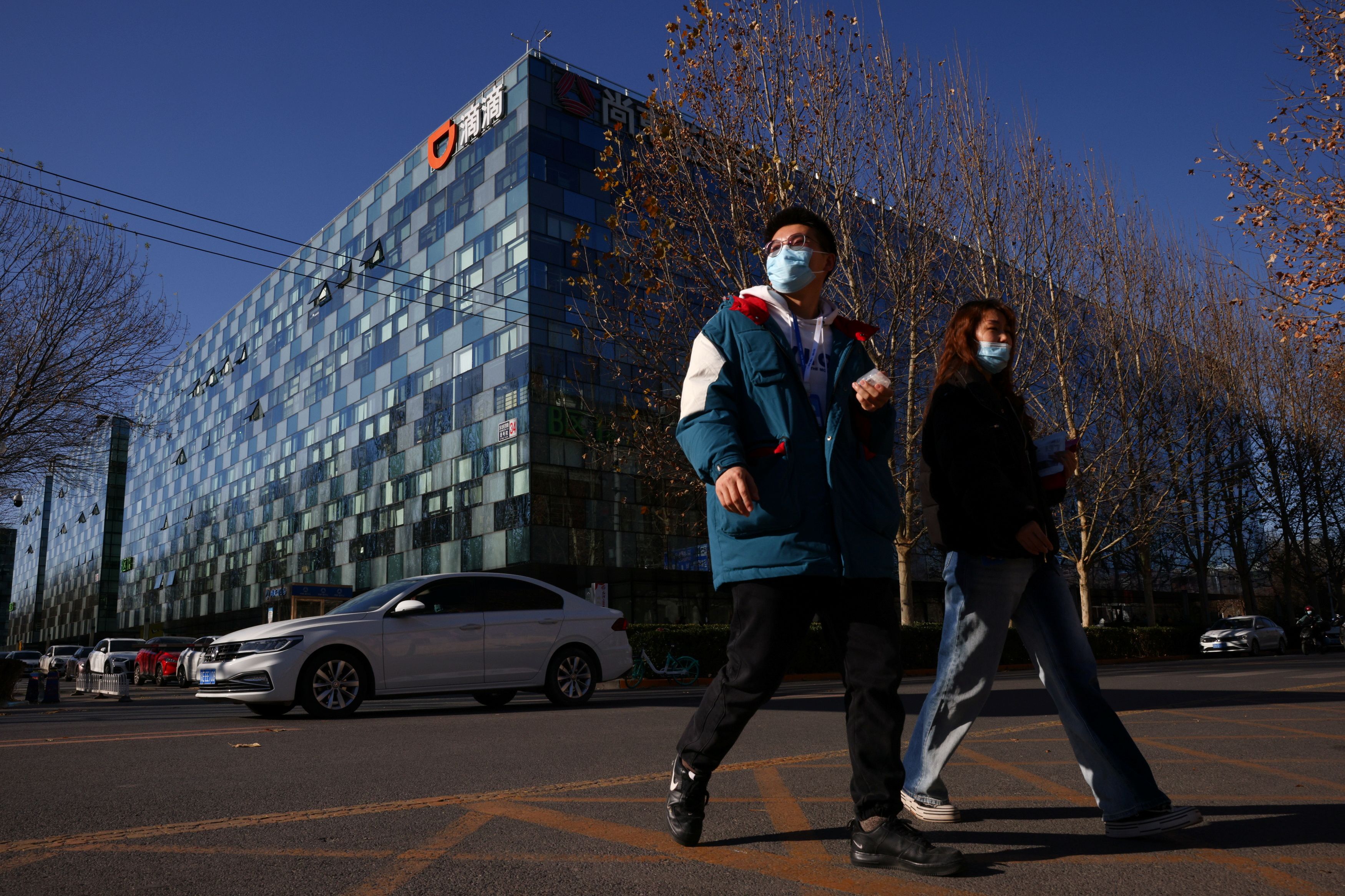 People walk past the headquarters of the Chinese ride-hailing service Didi in Beijing, China, December 3, 2021. REUTERS/Thomas Peter