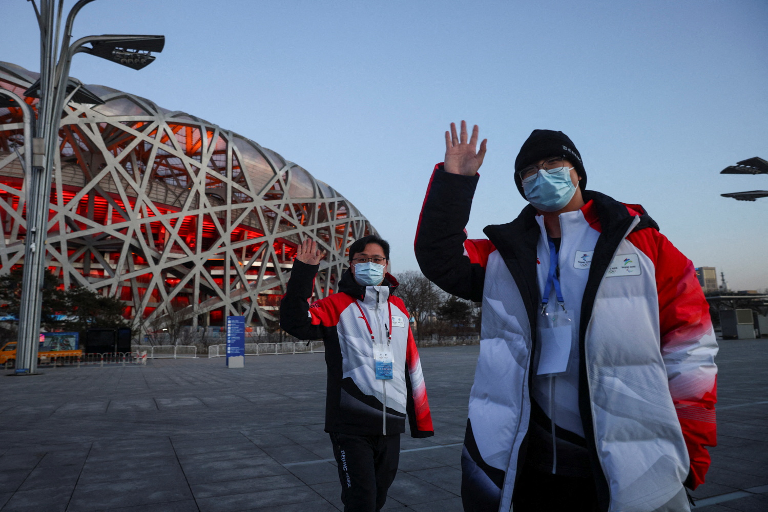 Staff members of the Beijing Olympic Organising Committee stand in front of the National Stadium, or Bird's Nest, the venue scheduled to hold the opening and closing ceremony of the Beijing 2022 Winter Olympics in Beijing