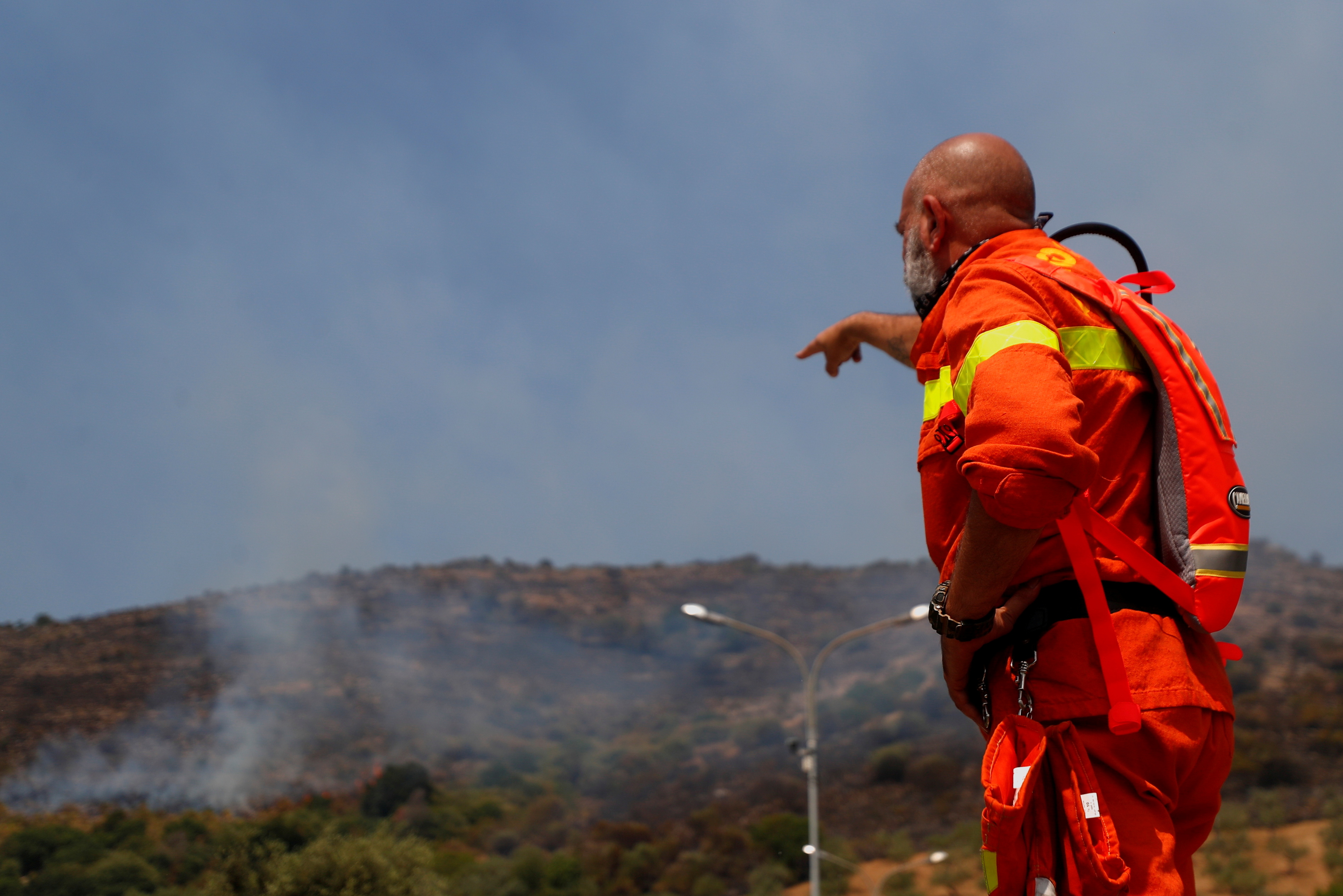 A firefighter points at a wildfire in the Monte Catillo nature reserve in Tivoli, near Rome, Italy, August 13, 2021. REUTERS/Guglielmo Mangiapane