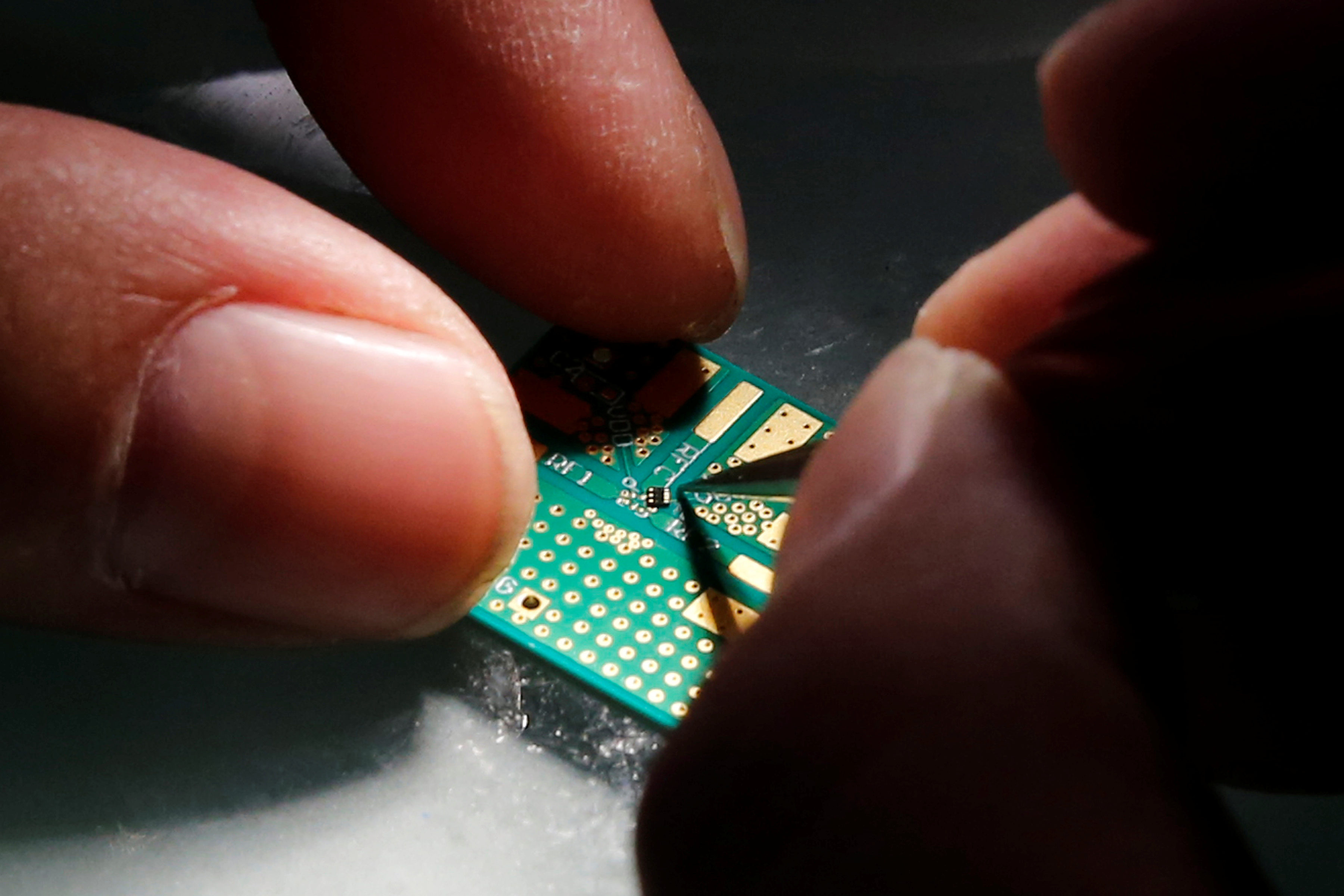 A researcher plants a semiconductor on an interface board during a research work to design and develop a semiconductor product at Tsinghua Unigroup research centre in Beijing