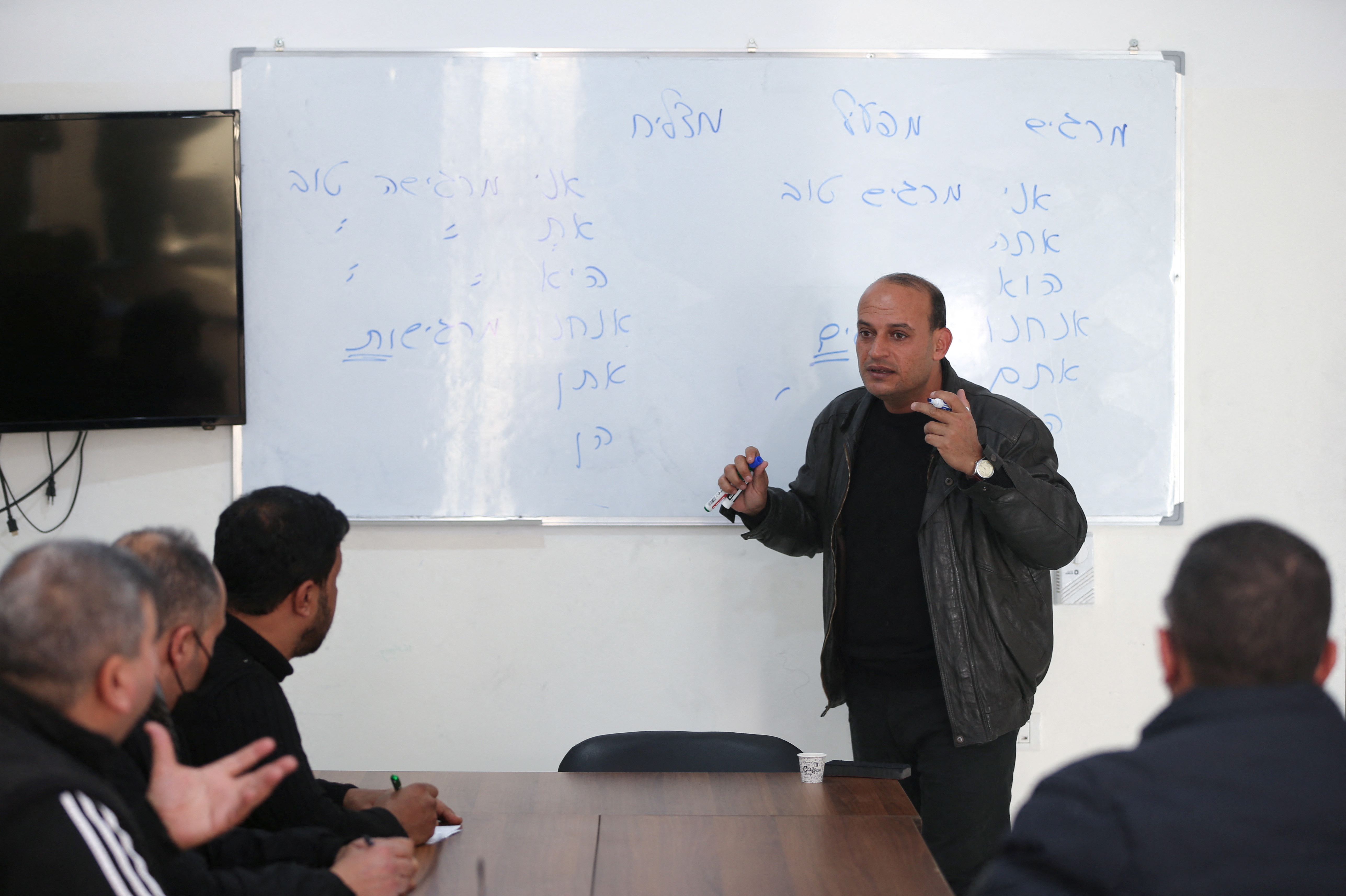 A Palestinian teacher teaches Hebrew language to a group of students at Nafha Language Center, in Khan Younis in the southern Gaza Strip February 16, 2022. REUTERS/Ibraheem Abu Mustafa