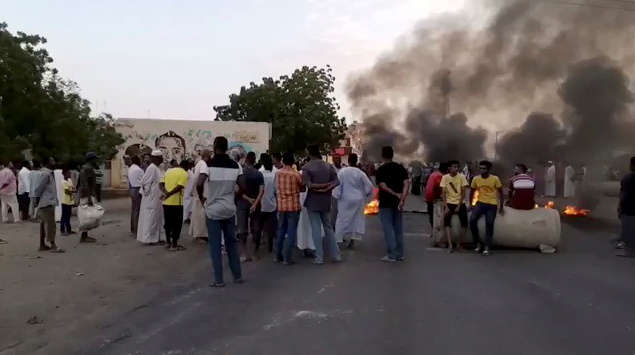 People gather around as smoke and fire are seen on the streets of Kartoum, Sudan, amid reports of a coup, October 25, 2021, in this still image from video obtained via social media. RASD SUDAN NETWORK via REUTERS
