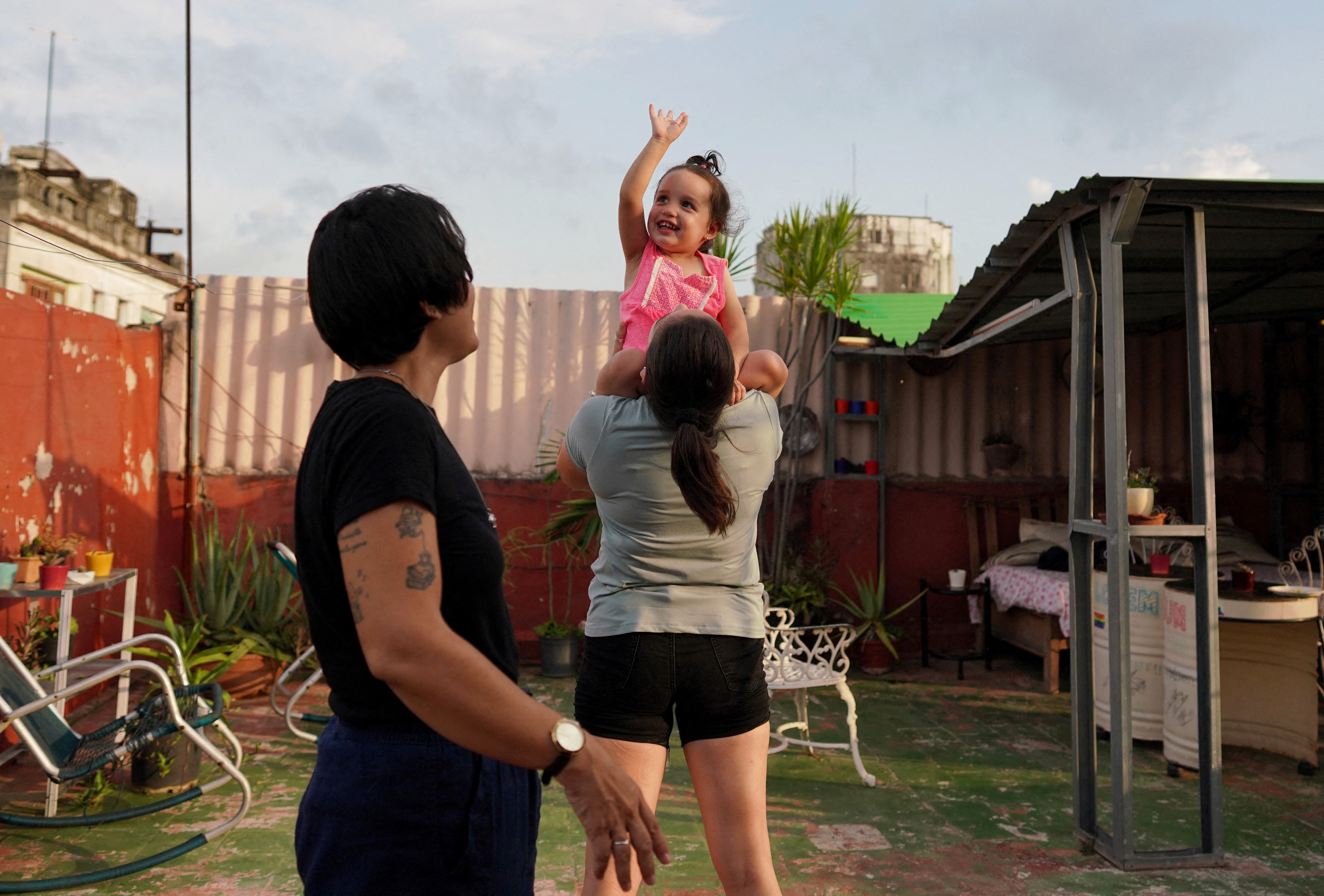 Couple Gabriela Alfonso Perez and Ria Acosta plays in their garden in Havana