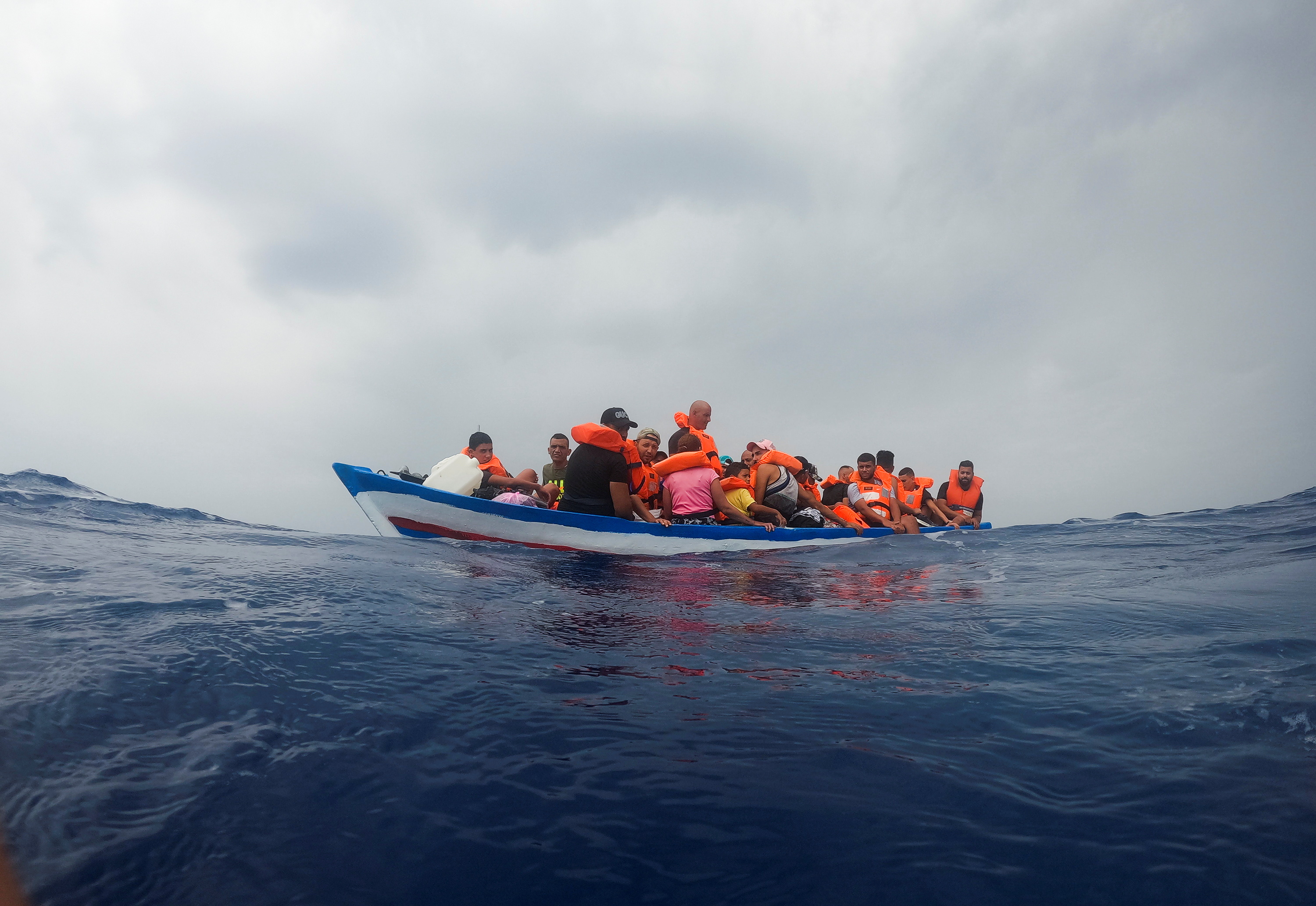 Migrants on a wooden boat wait for the Italian Guardia Costiera near the island of Lampedusa, in the Mediterranean Sea, September 1, 2021. REUTERS/Juan Medina