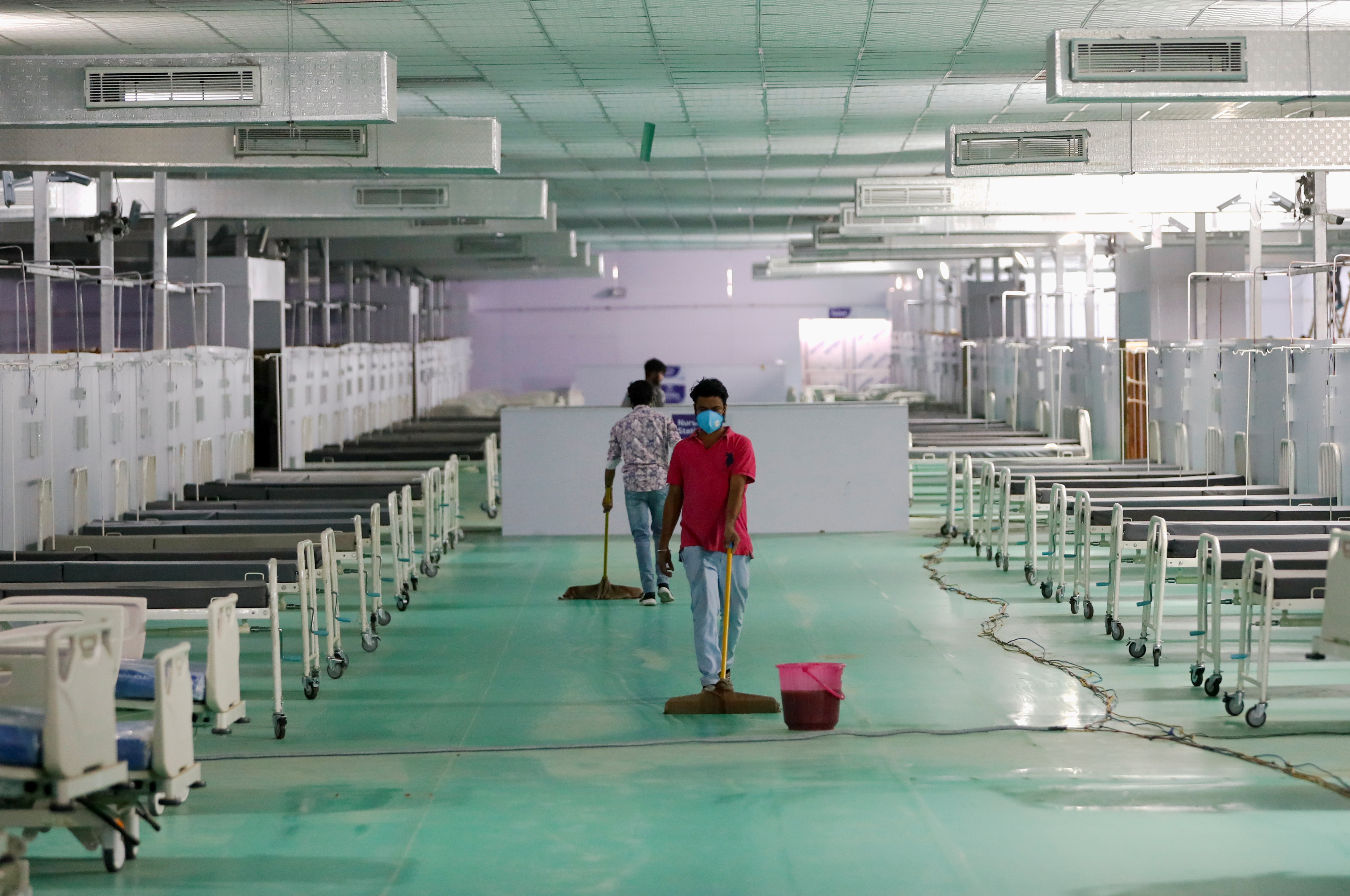 Workers clean floor at temporary COVID-19 care facility in New Delhi