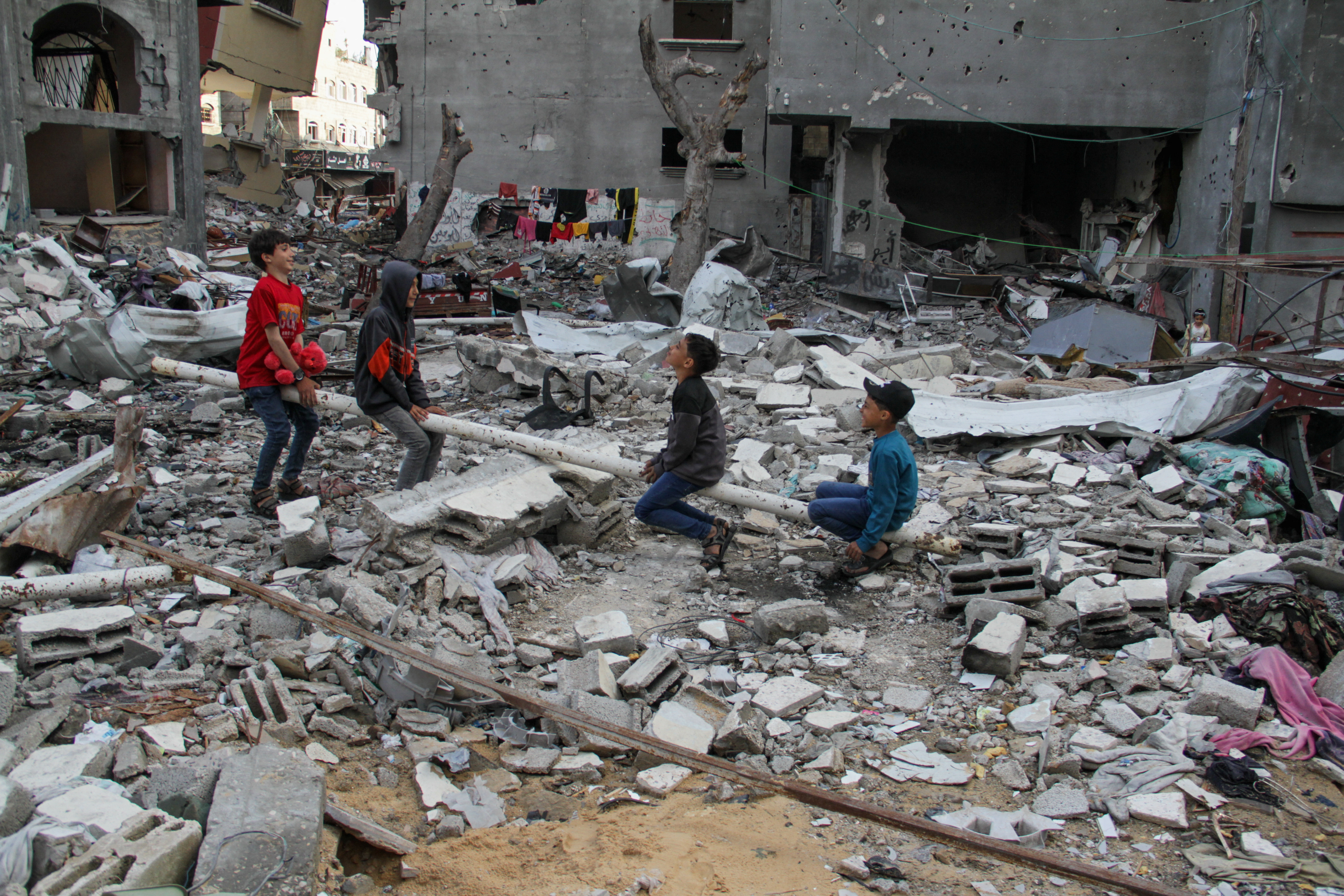 People sit amid rubble during Eid al-Fitr, in Gaza City