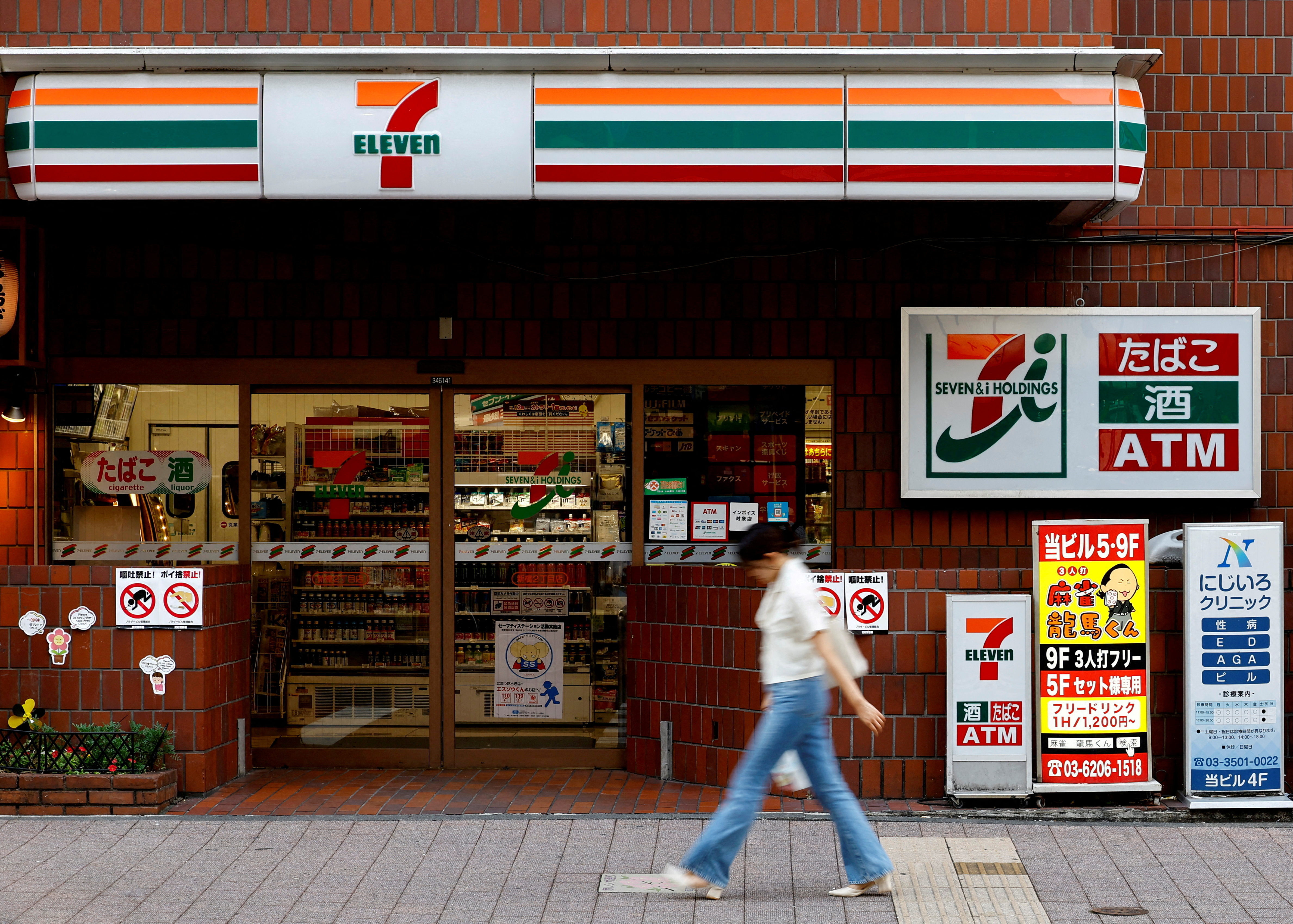 FILE PHOTO: A pedestrian walks past Japan's Seven & I’s 7-Eleven convenience store in Tokyo