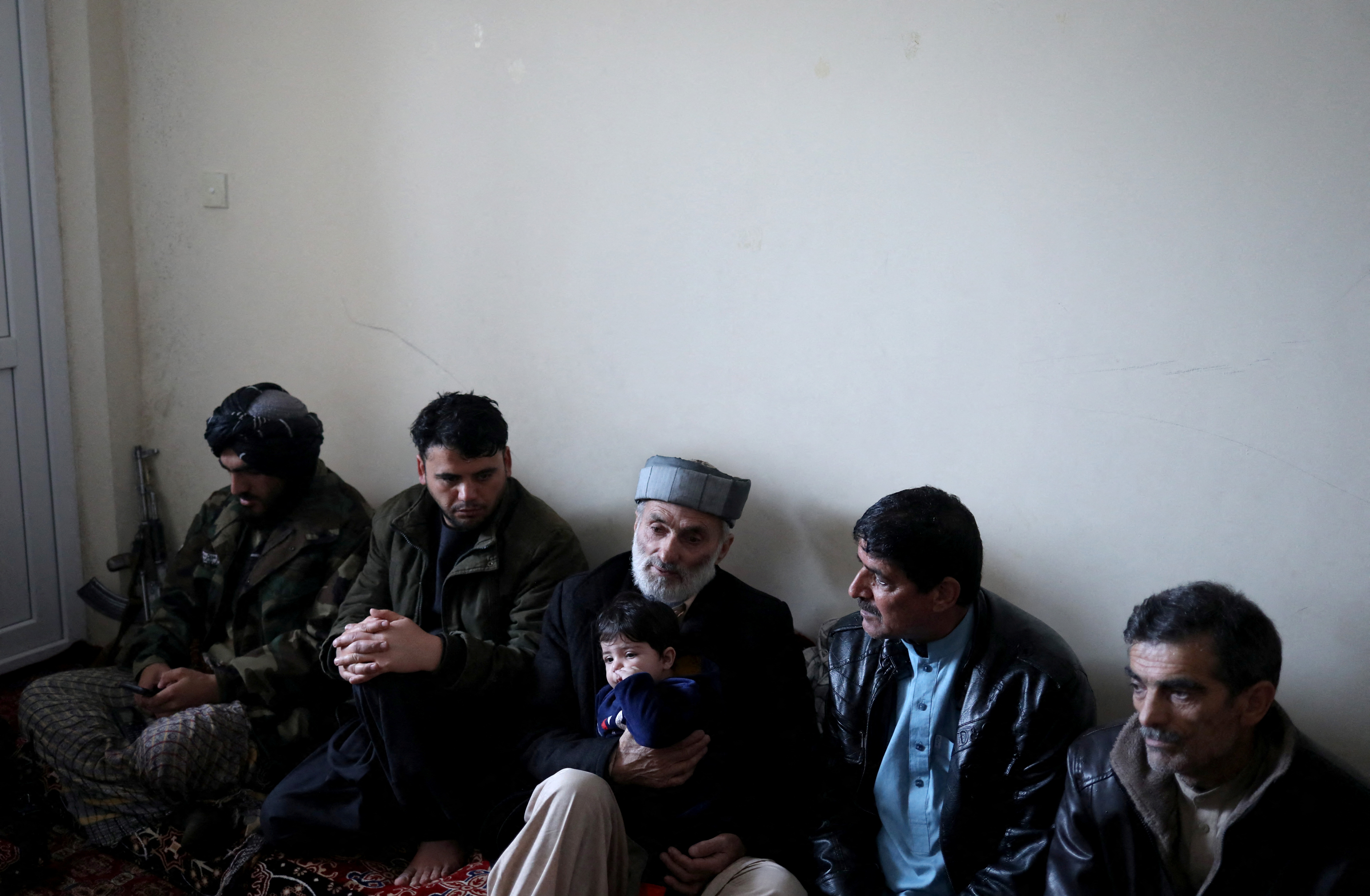 Mohammad Qasem Razawi, grandfather of baby Sohail Ahmadi, holds him at the house of Hamid Safi in Kabul
