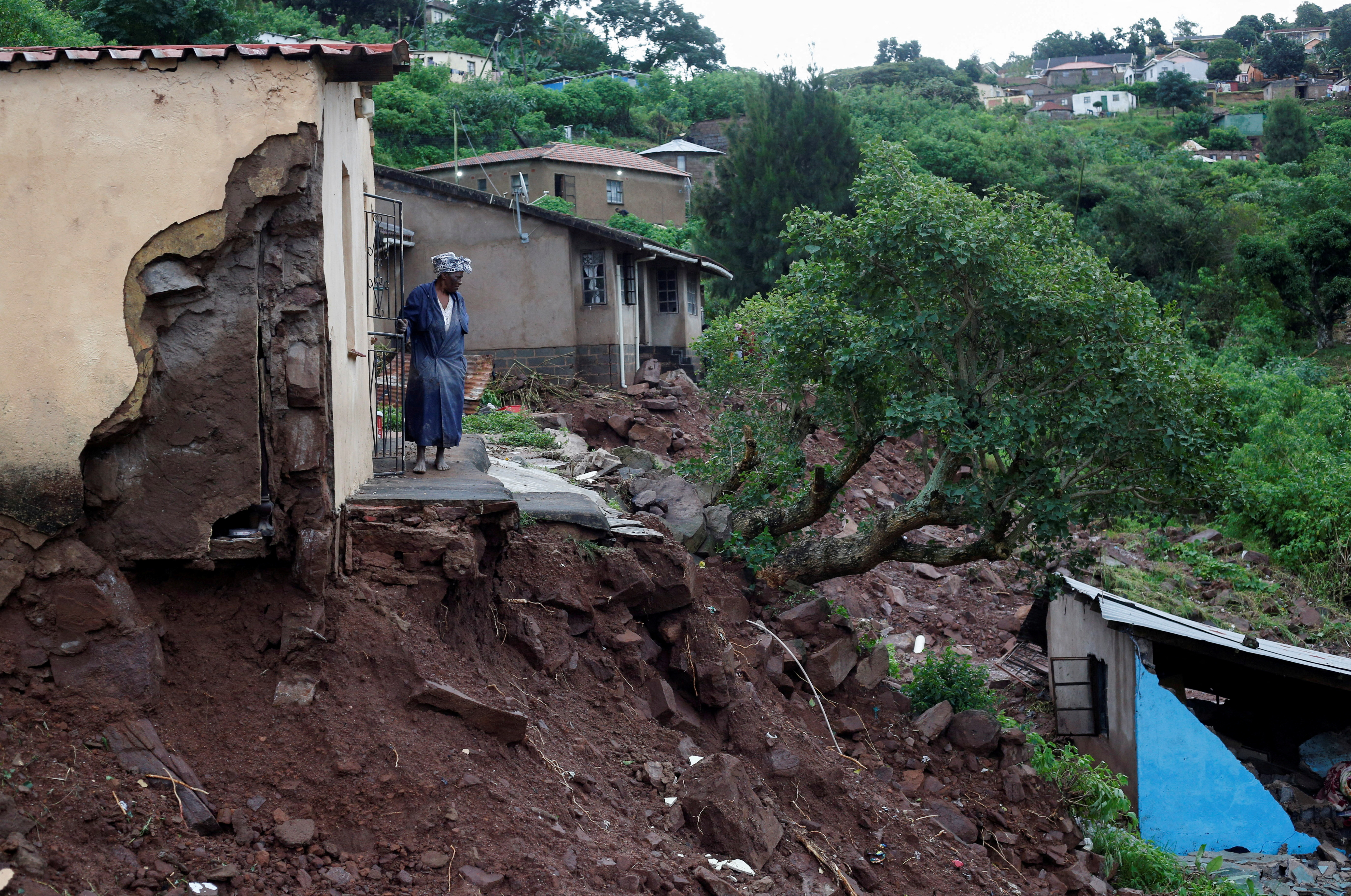 A woman stands at her front door after heavy rains caused flood damage in KwaNdengezi, Durban,