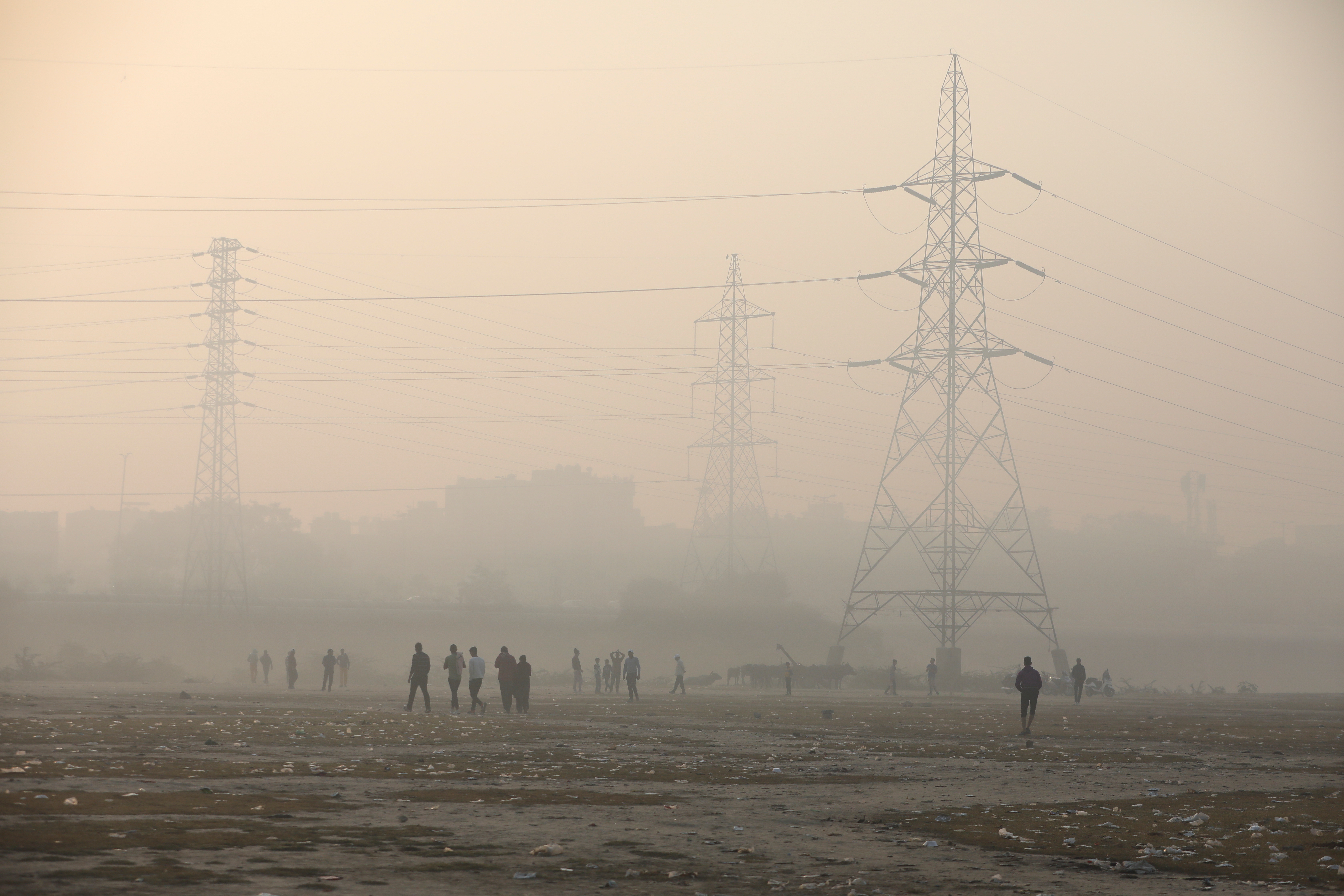 People are seen on the floodplains of the Yamuna river on a smoggy morning in New Delhi