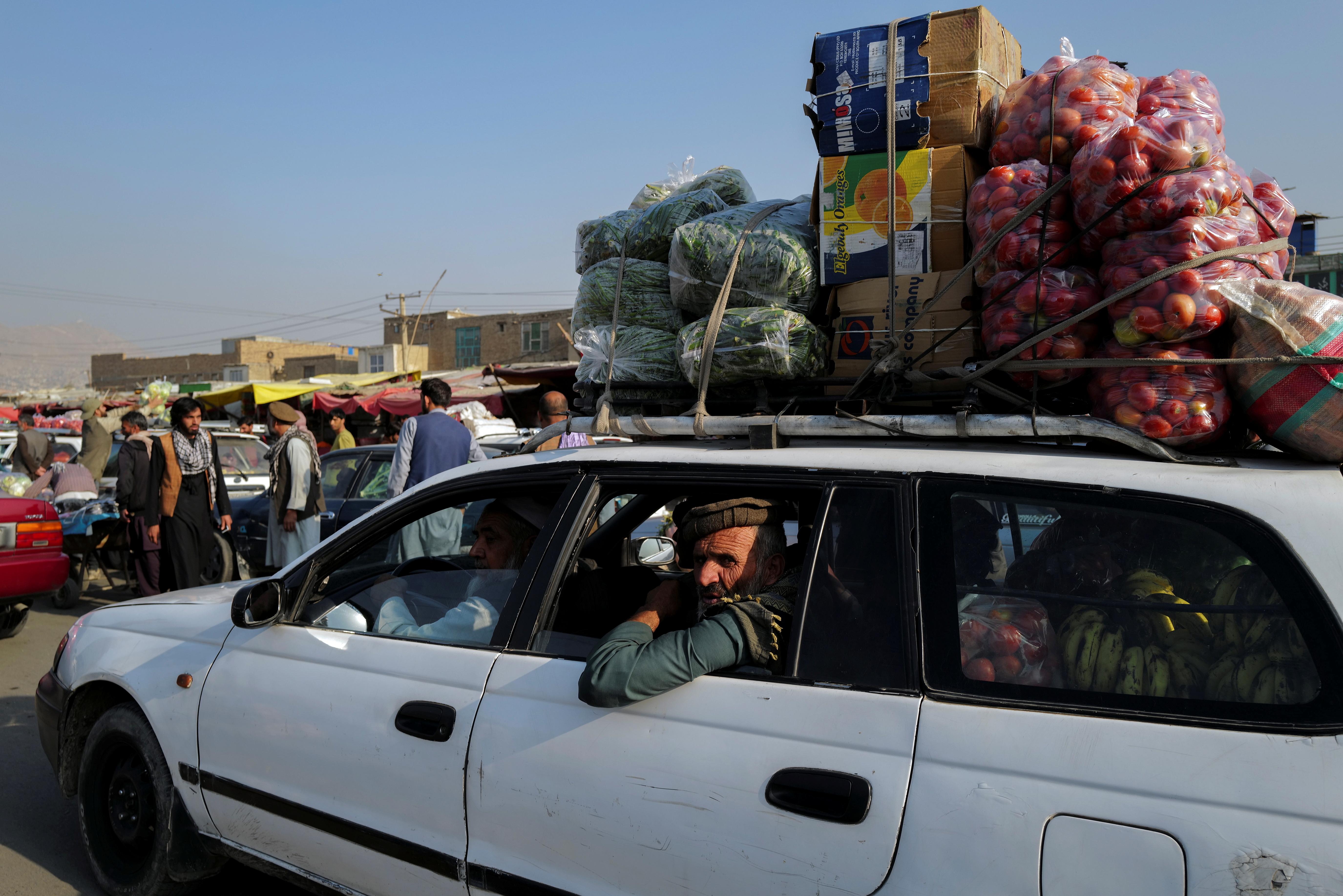 A man rides a car filled with vegetables and fruits for sale at the market in Kabul
