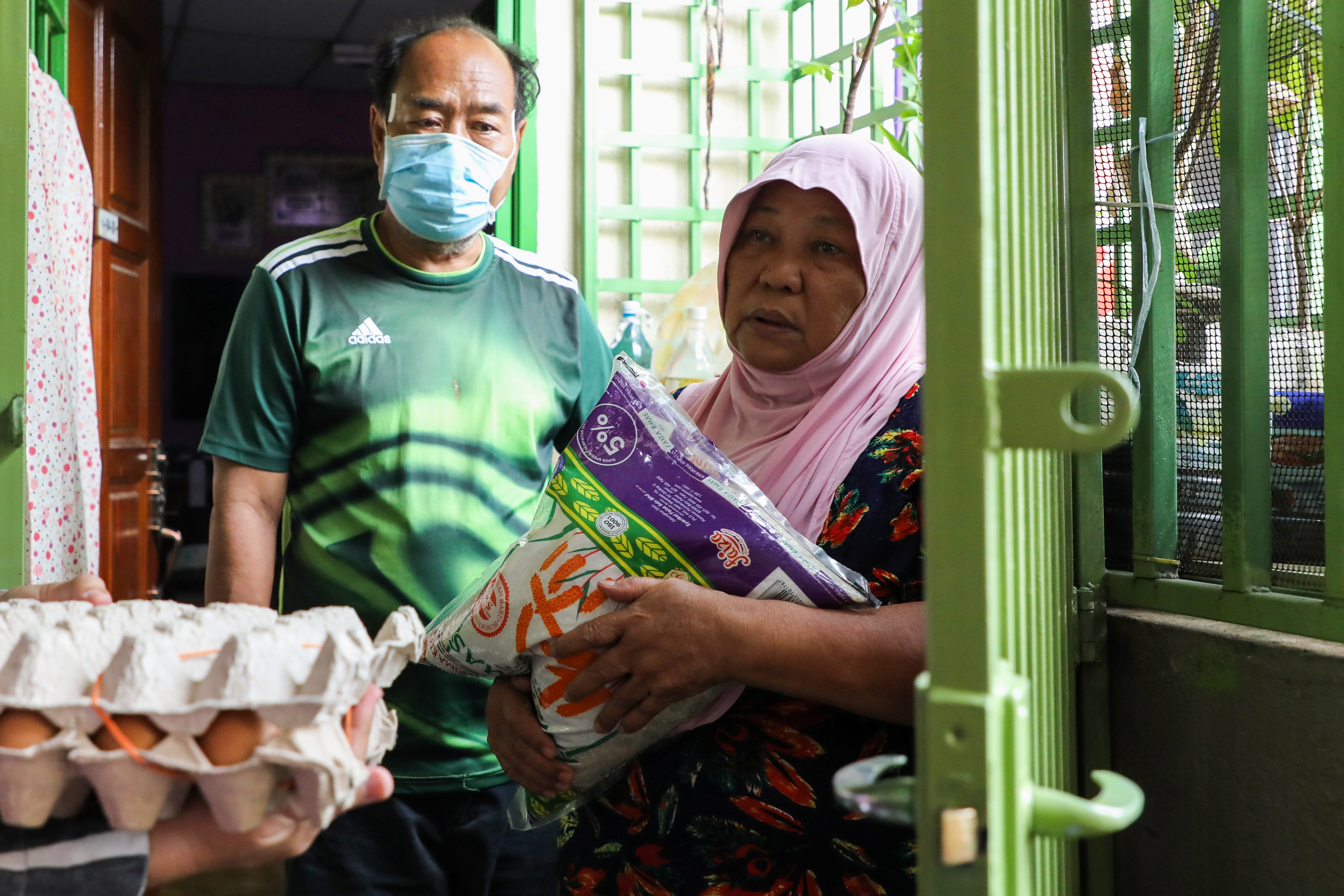 Halijah Naemat, 74, receives food supplies after she hung a white flag outside her home asking for help during an enhanced lockdown in Petaling Jaya