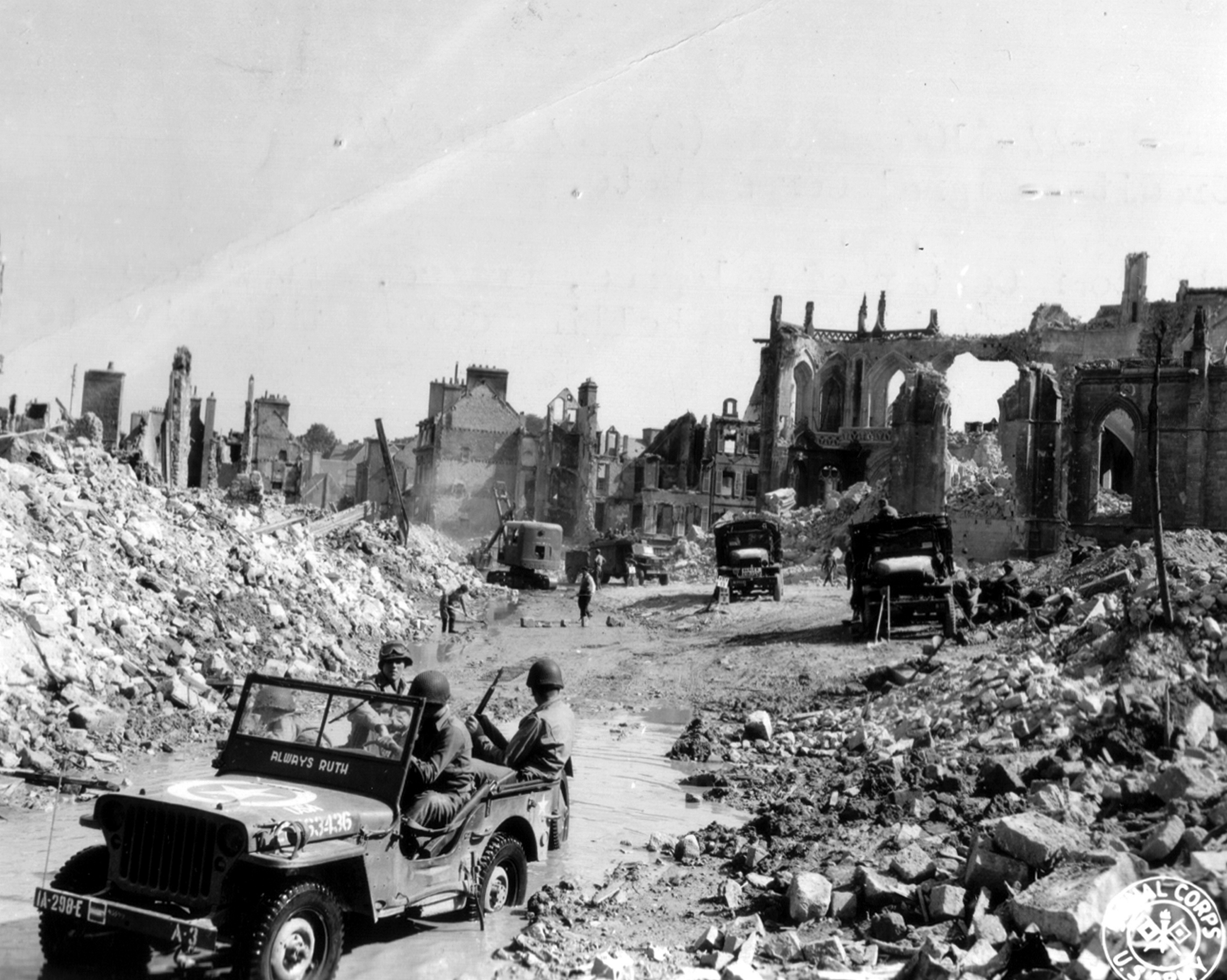 A jeep of U.S. Army combat engineers unit drives past the destroyed Saint Malo church following the D-Day landings operation in Valognes in this handout photo