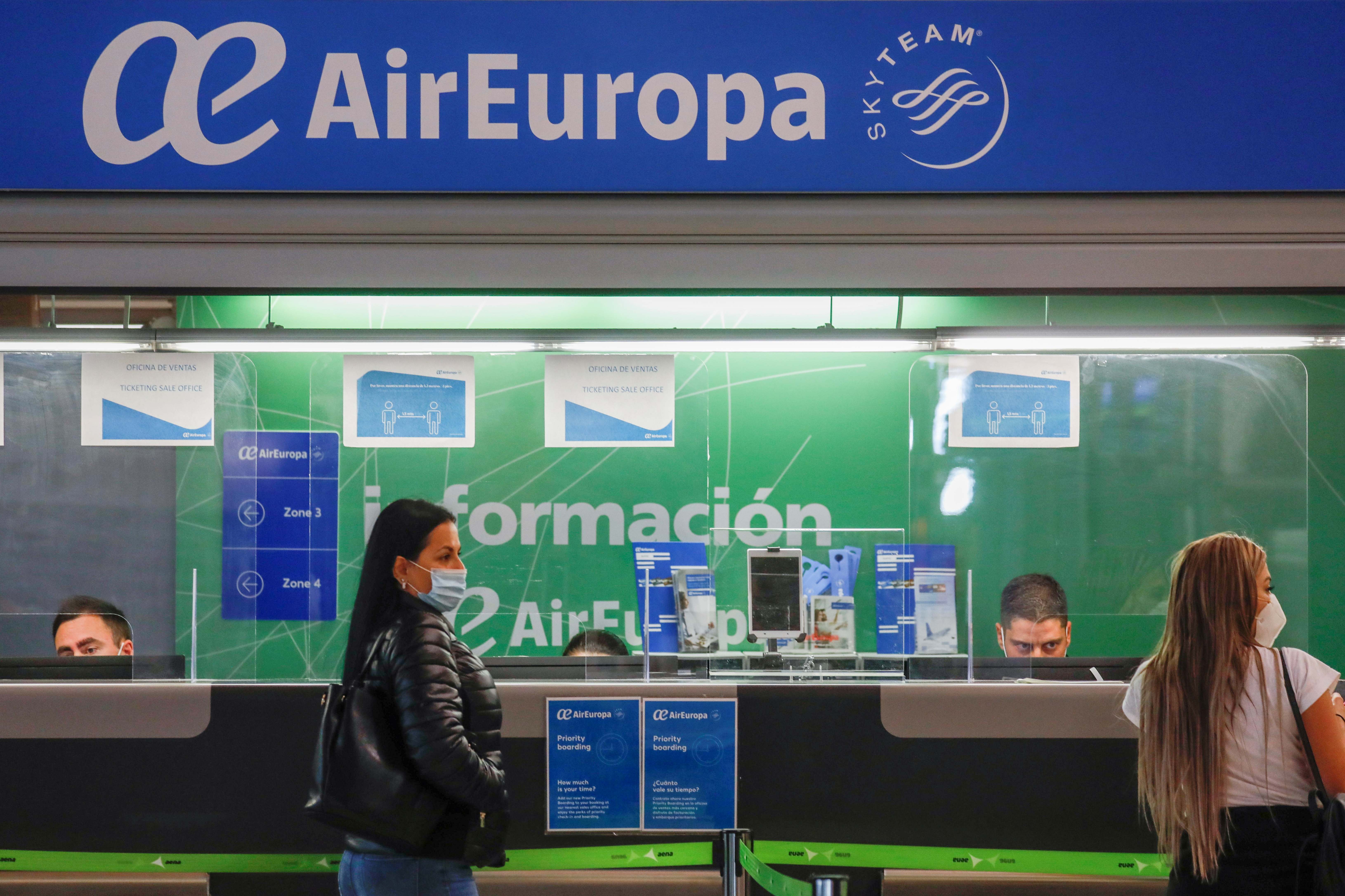 Passengers wearing facemasks stand at an Air Europa customer service booth at Adolfo Suarez Barajas airport amid the coronavirus disease (COVID-19) pandemic in Madrid