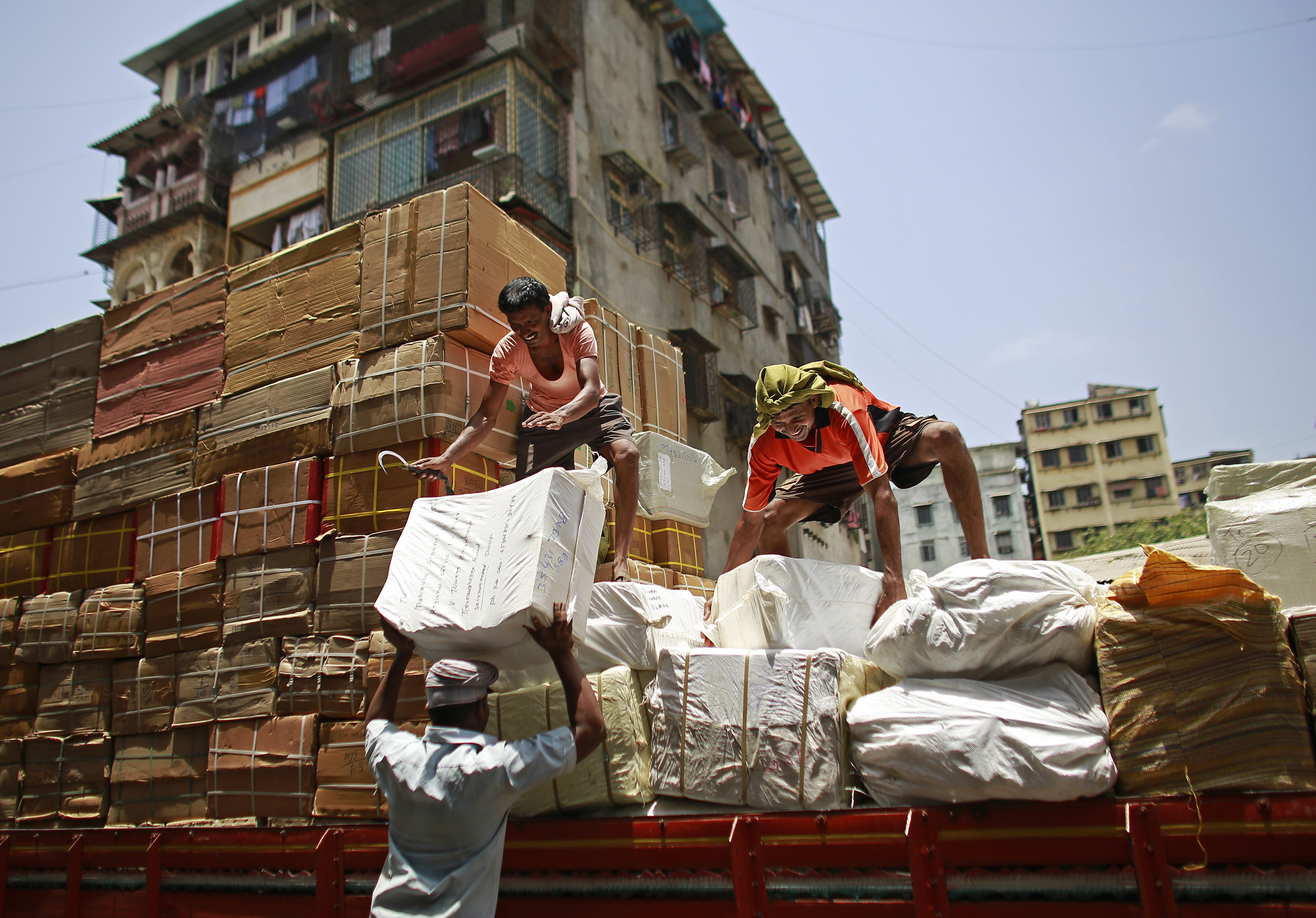 Workers of a transport company load packages on a truck at a wholesale market in Mumbai