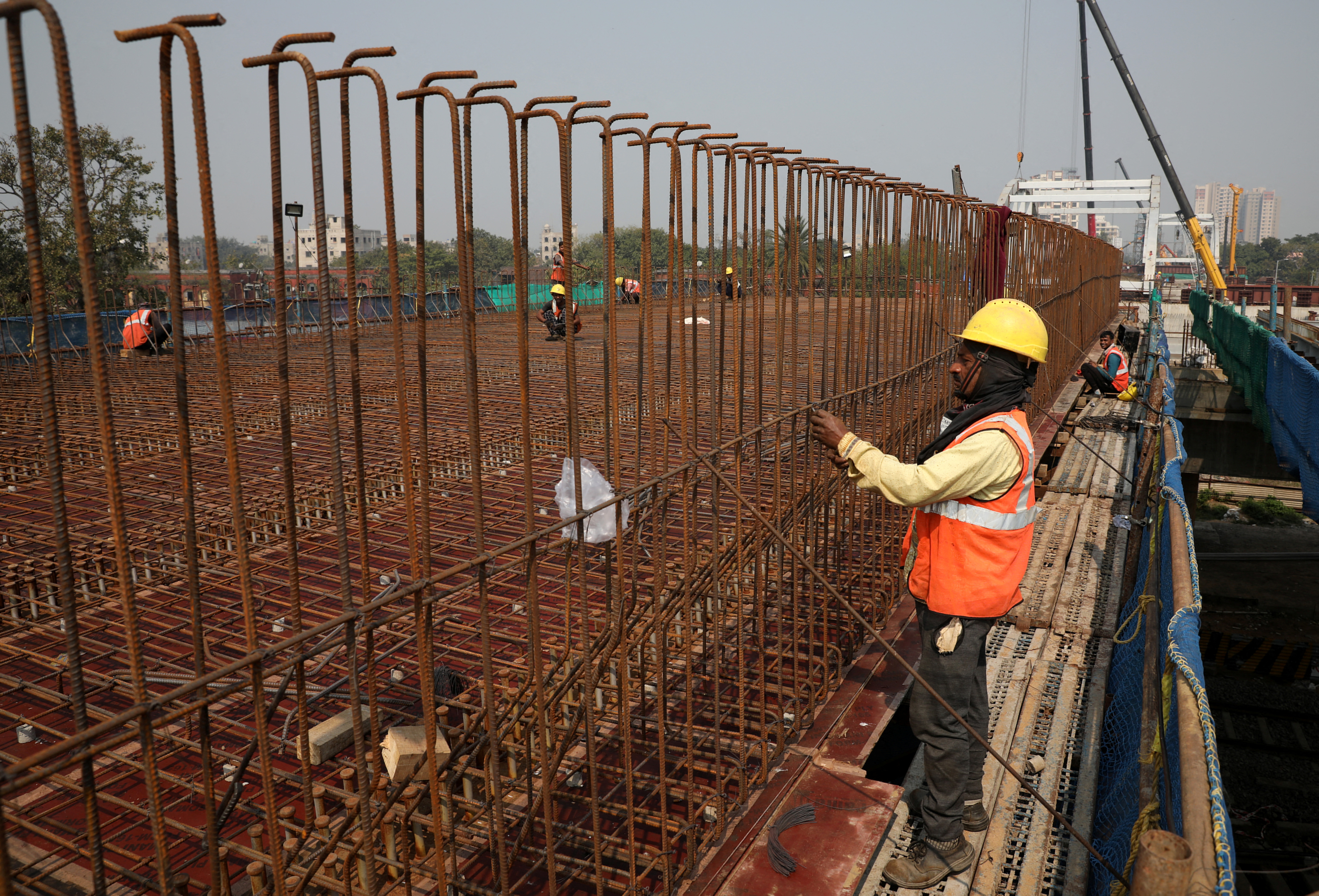 Workers tie irons rods at the site of an under construction flyover in Kolkata