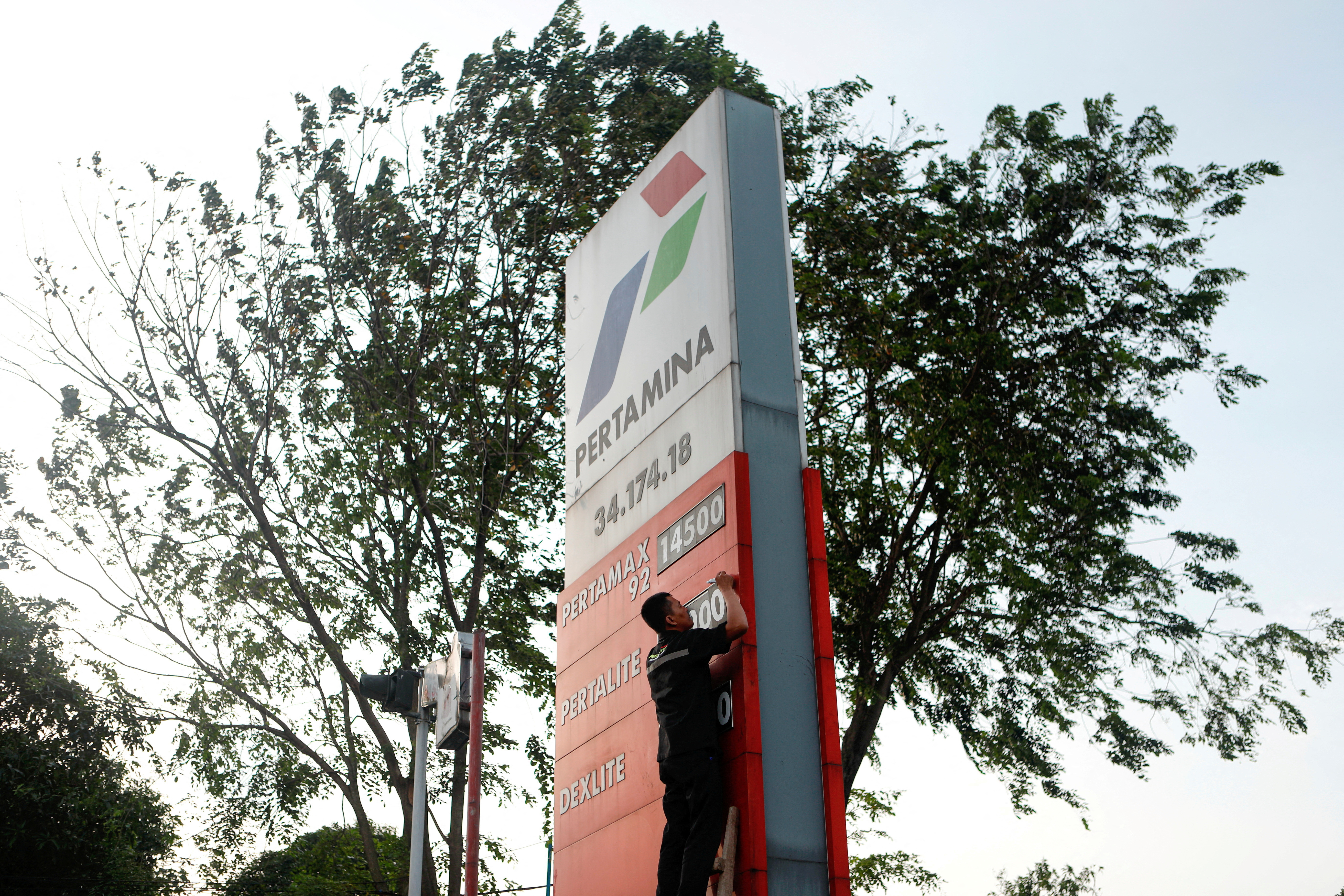 A worker of a petrol station of the state-owned company Pertamina changes the fuel prices displayed after the announcement of a fuel price hike, in Bekasi