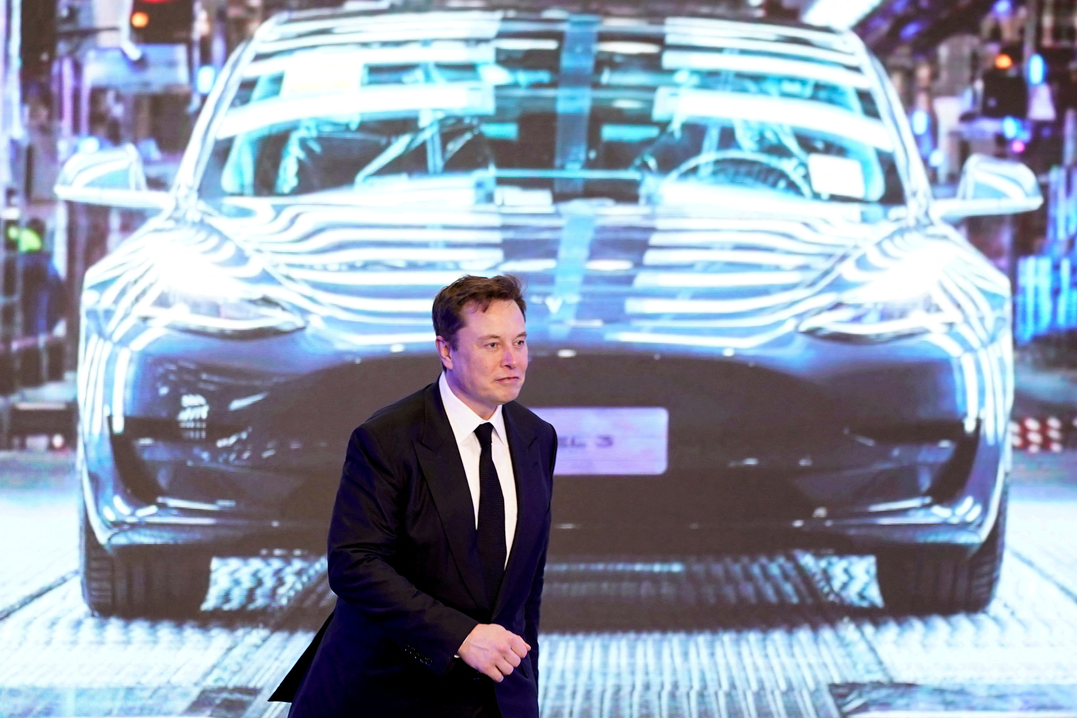 Tesla Inc CEO Elon Musk walks next to a screen showing an image of Tesla Model 3 car during an opening ceremony for Tesla China-made Model Y program in Shanghai