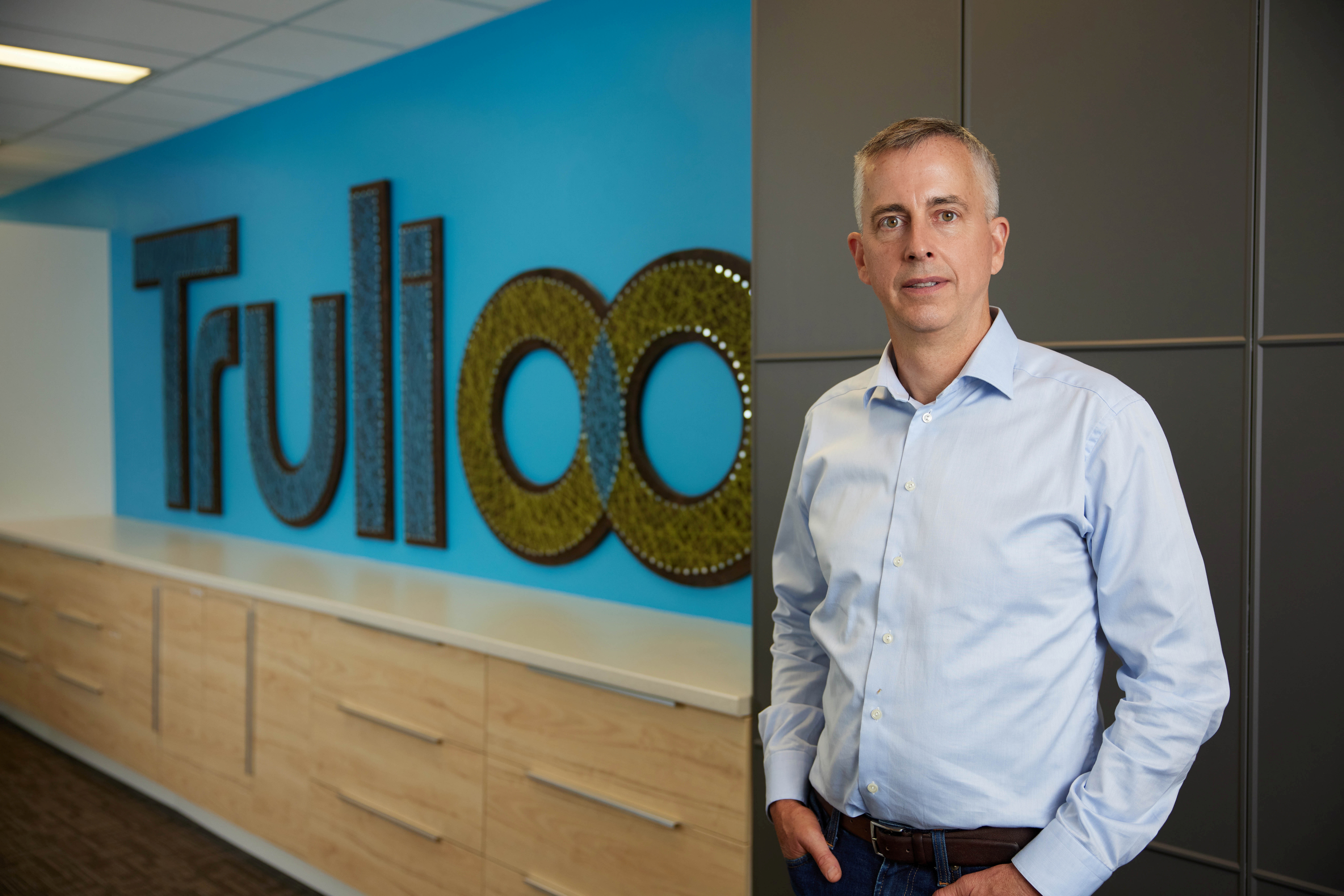 Steve Munford, CEO of Trulioo, a Canadian-based startup that provides electronic identity and address verification globally, poses in front of the company logo in this undated handout photo