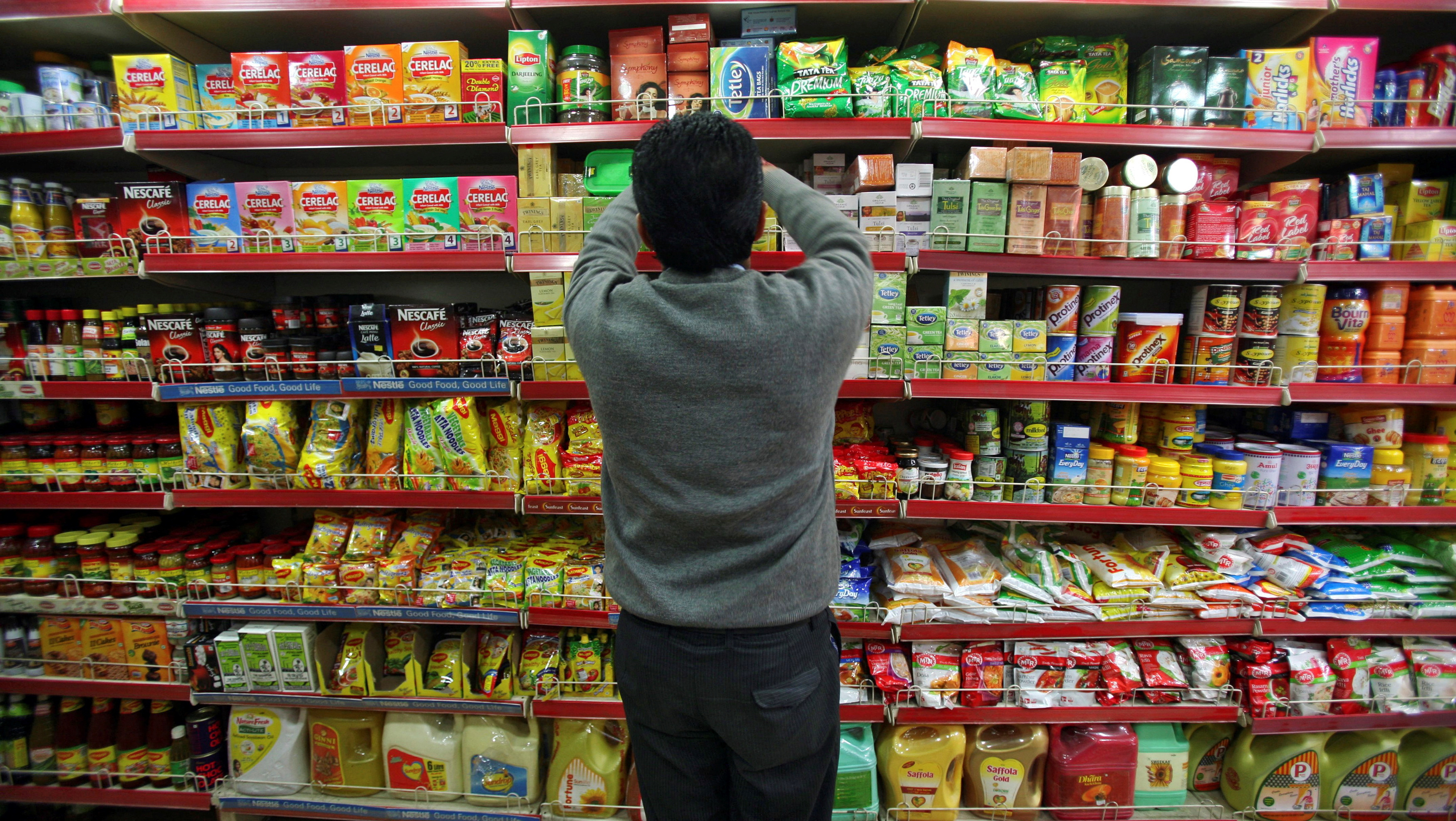 A worker arranges consumable goods at a grocery store in Jammu