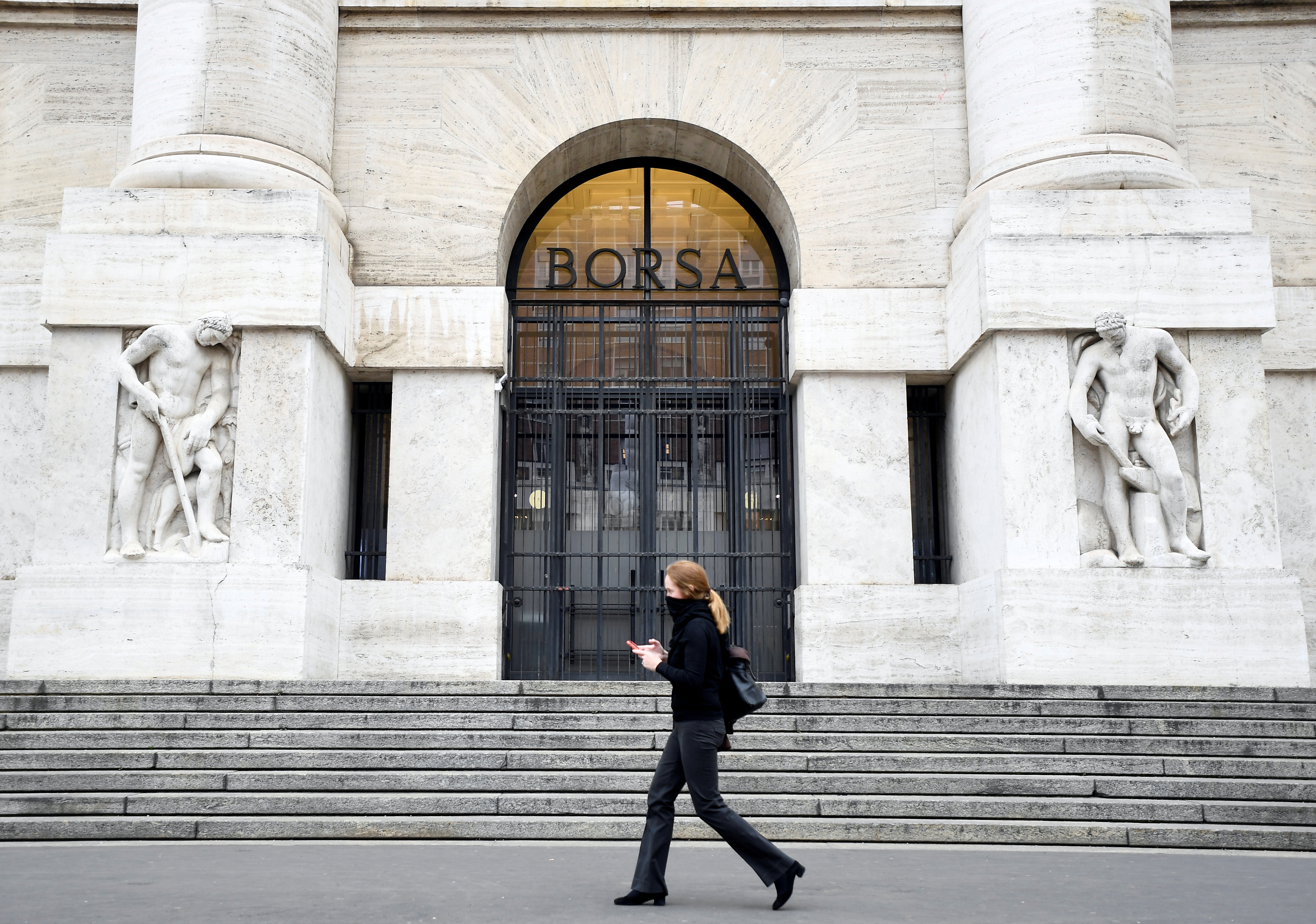 Woman goes past the Italian Stock Exchange in Milan