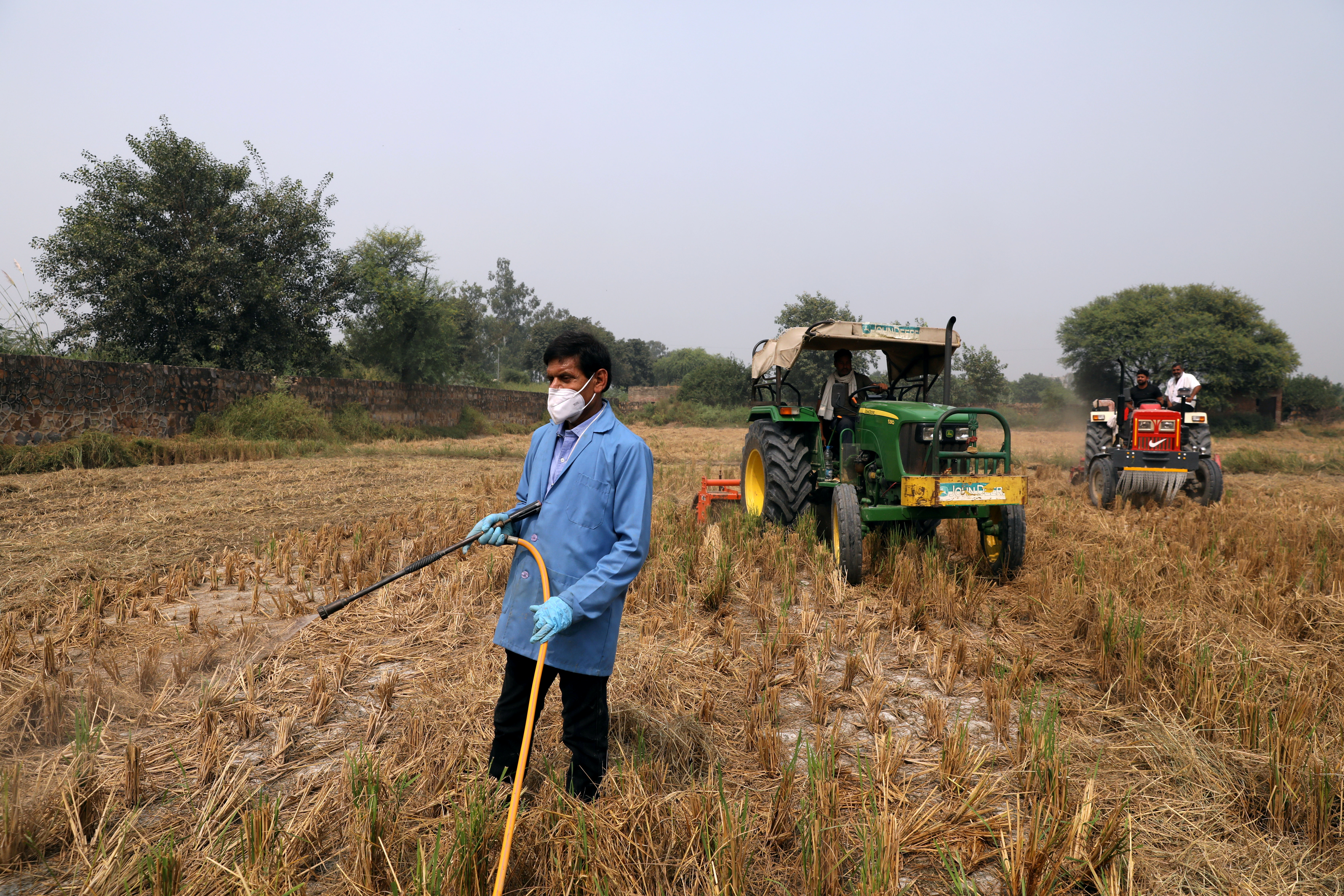 A man sprays newly-developed bio-decomposer solution in a field to prevent stubble burning, in New Delhi