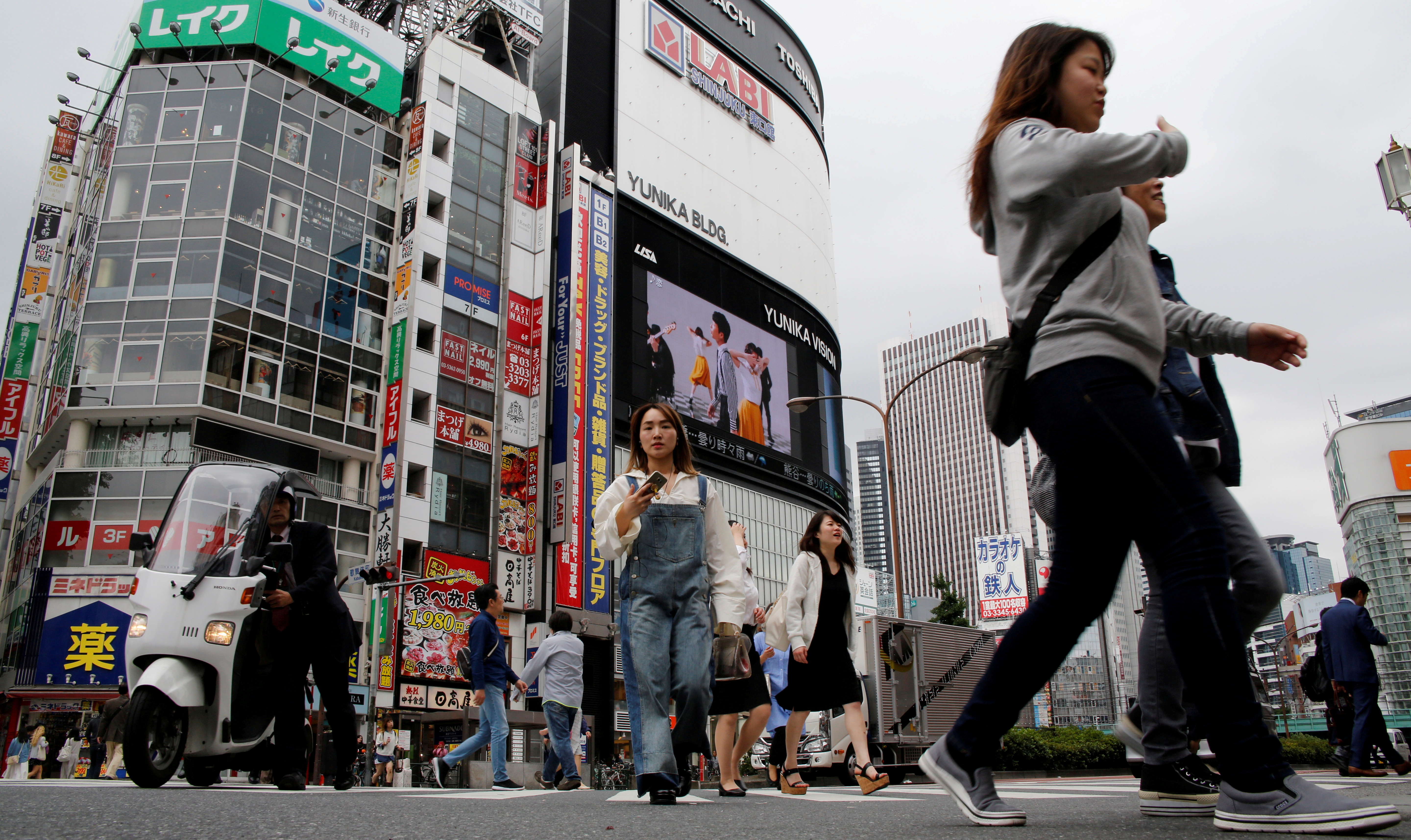 People cross a street in the Shinjuku shopping and business district in Tokyo