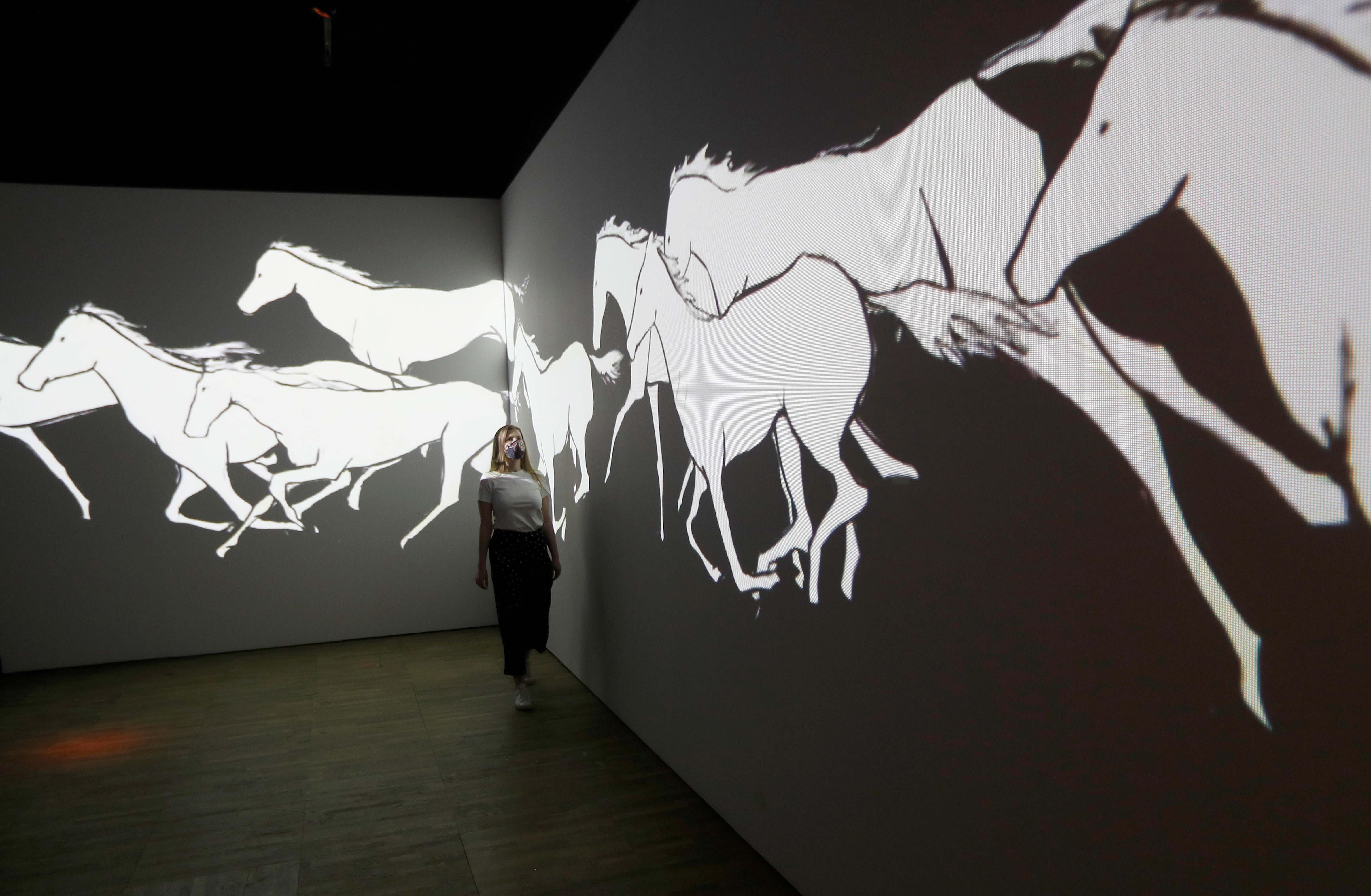 A V&A employee looks at All the White Horses, a hand drawn video animation by Avish Khebrehzadeh, on display in Epic Iran, an exhibition soon to open at the V&A in London, Britain, May 25, 2021.  REUTERS/Peter Nicholls