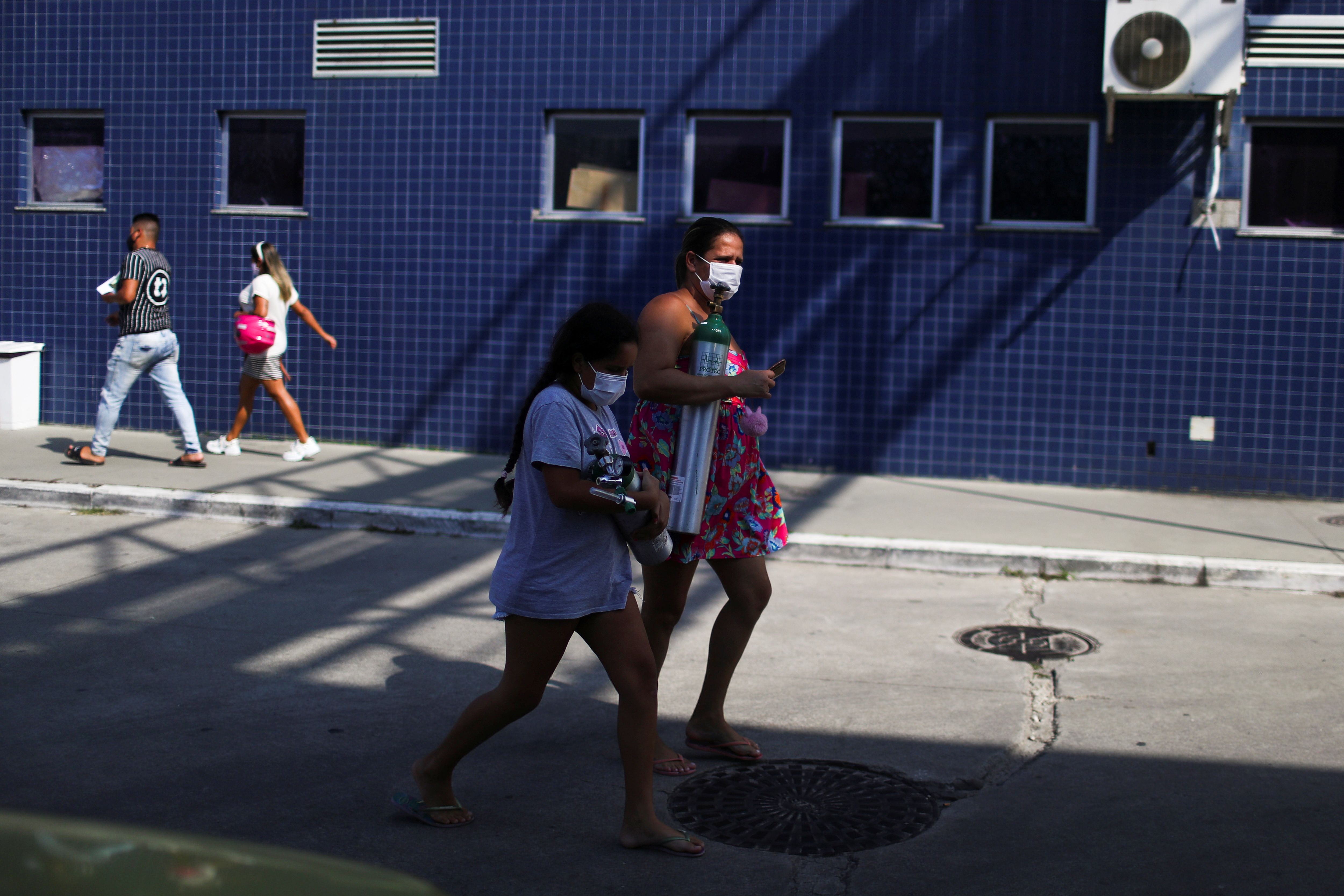 A woman and a child hold oxygen tanks, amid the coronavirus disease (COVID-19) outbreak, in the Moacyr do Carmo hospital in Duque de Caxias near Rio de Janeiro, Brazil May 20, 2021. REUTERS/Pilar Olivares