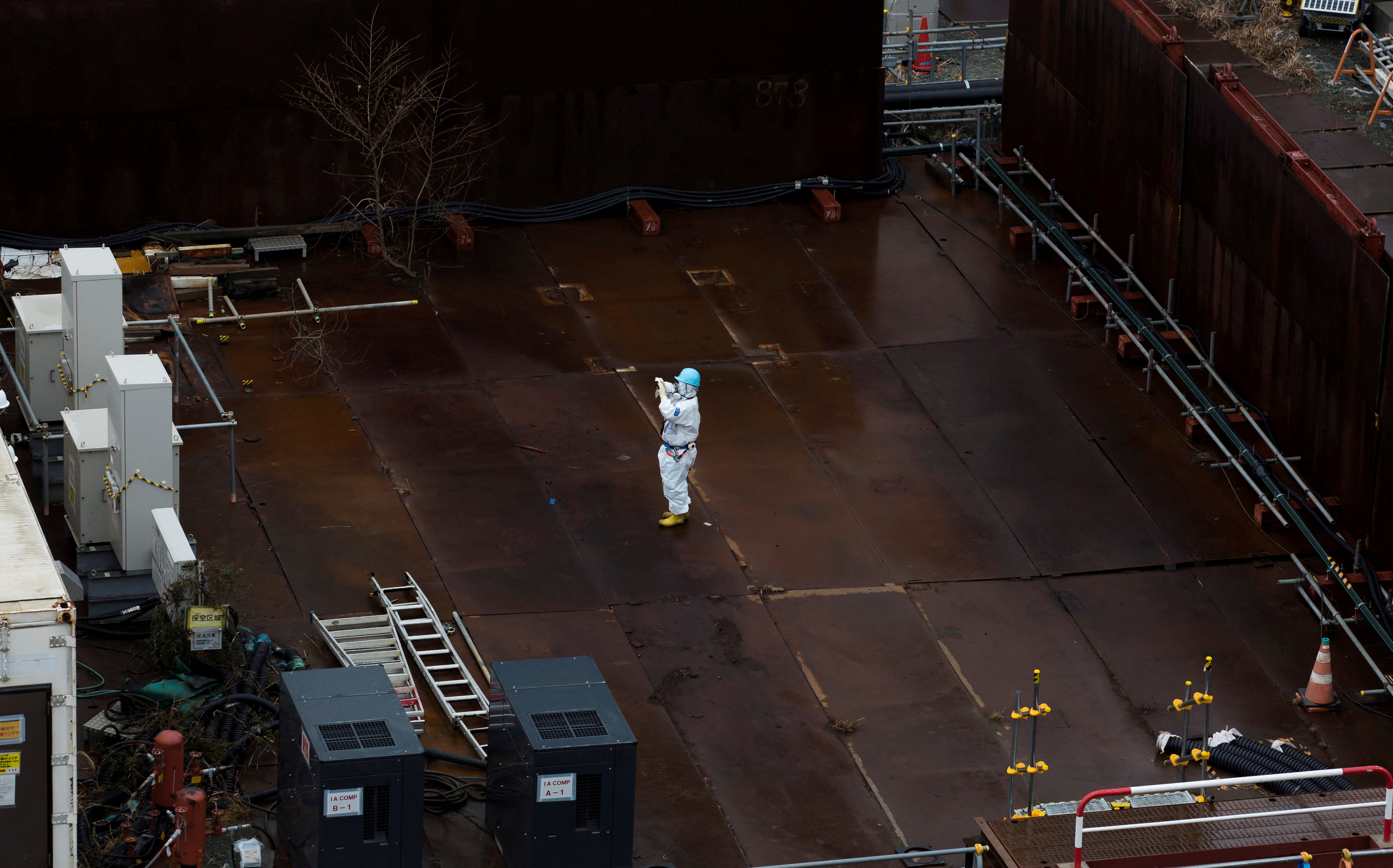 A worker wearing a protective suit and a mask take photograph at TEPCO's Fukushima Daiichi nuclear power plant in Okuma