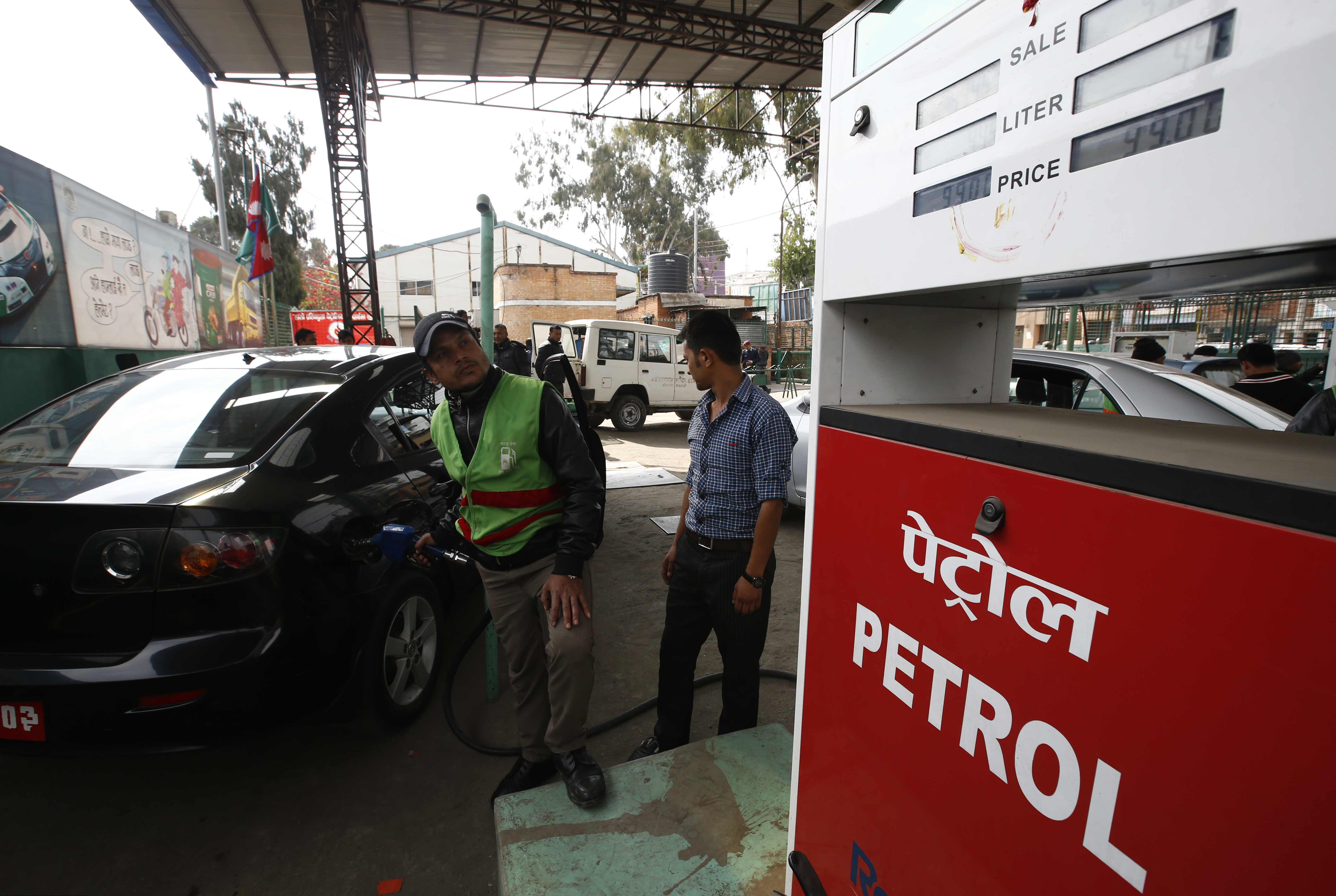 A petrol pump attendant (L) fills petrol for 99 NRS equivalent to 0.91 USD per litre on a car at Saja Petrol pump after the price for petrol decreased from 104 NRS equivalent to 0.96 USD per litre