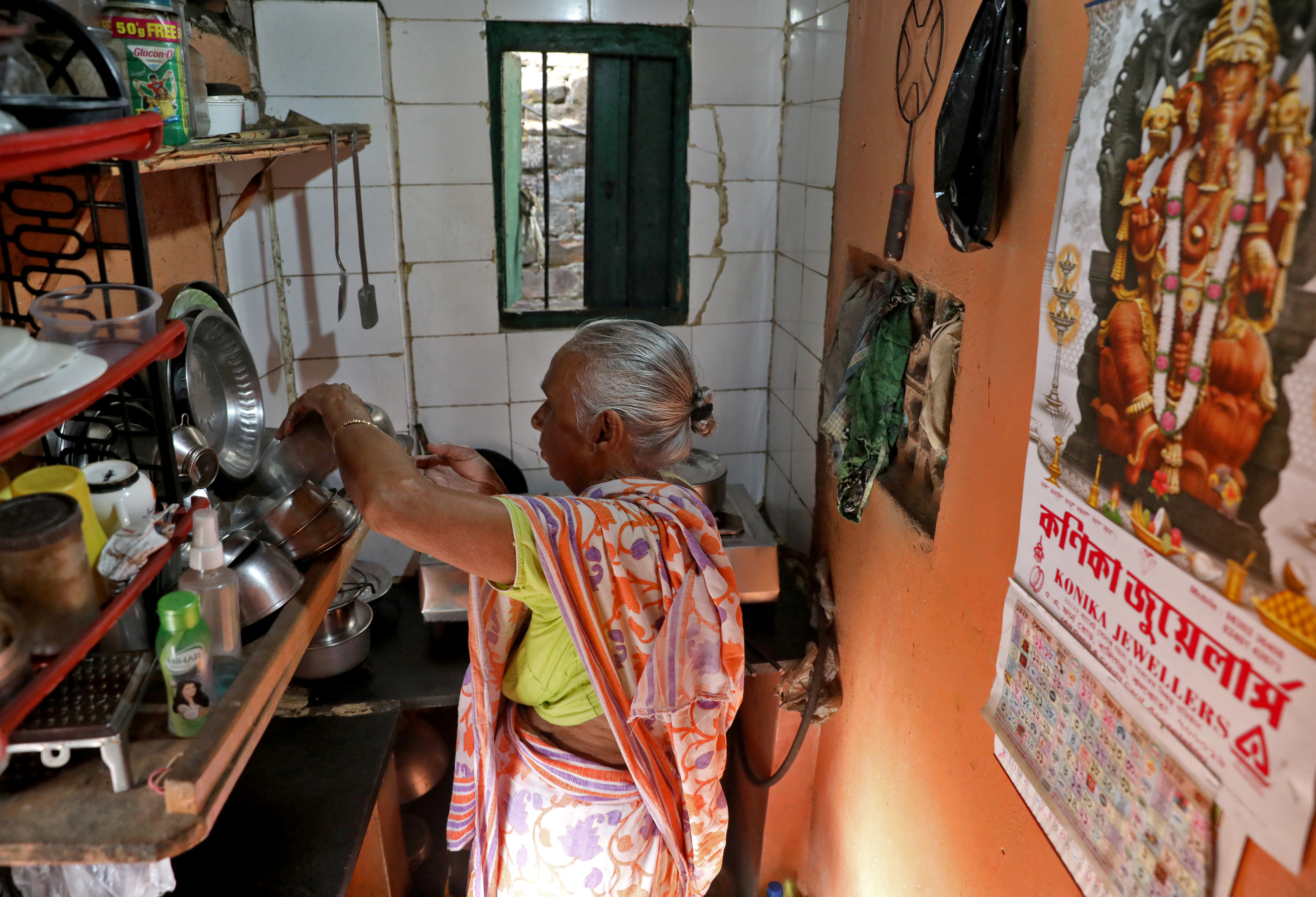Gita Sen prepares her morning tea inside her rented one-room in a slum in Kolkata