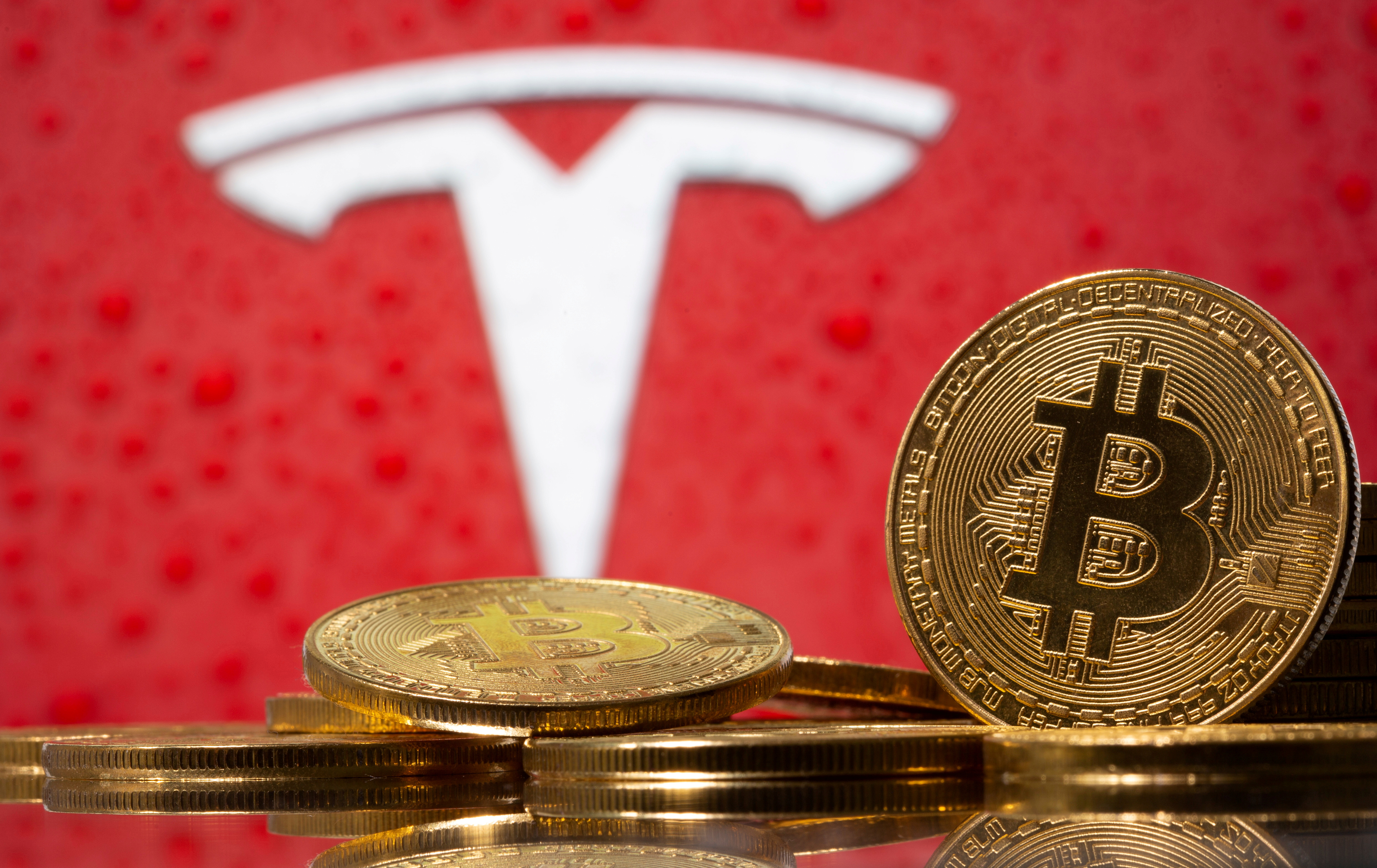 Representations of virtual currency Bitcoin are seen in front of Tesla logo in this illustration taken, February 9, 2021. REUTERS/Dado Ruvic/File Photo