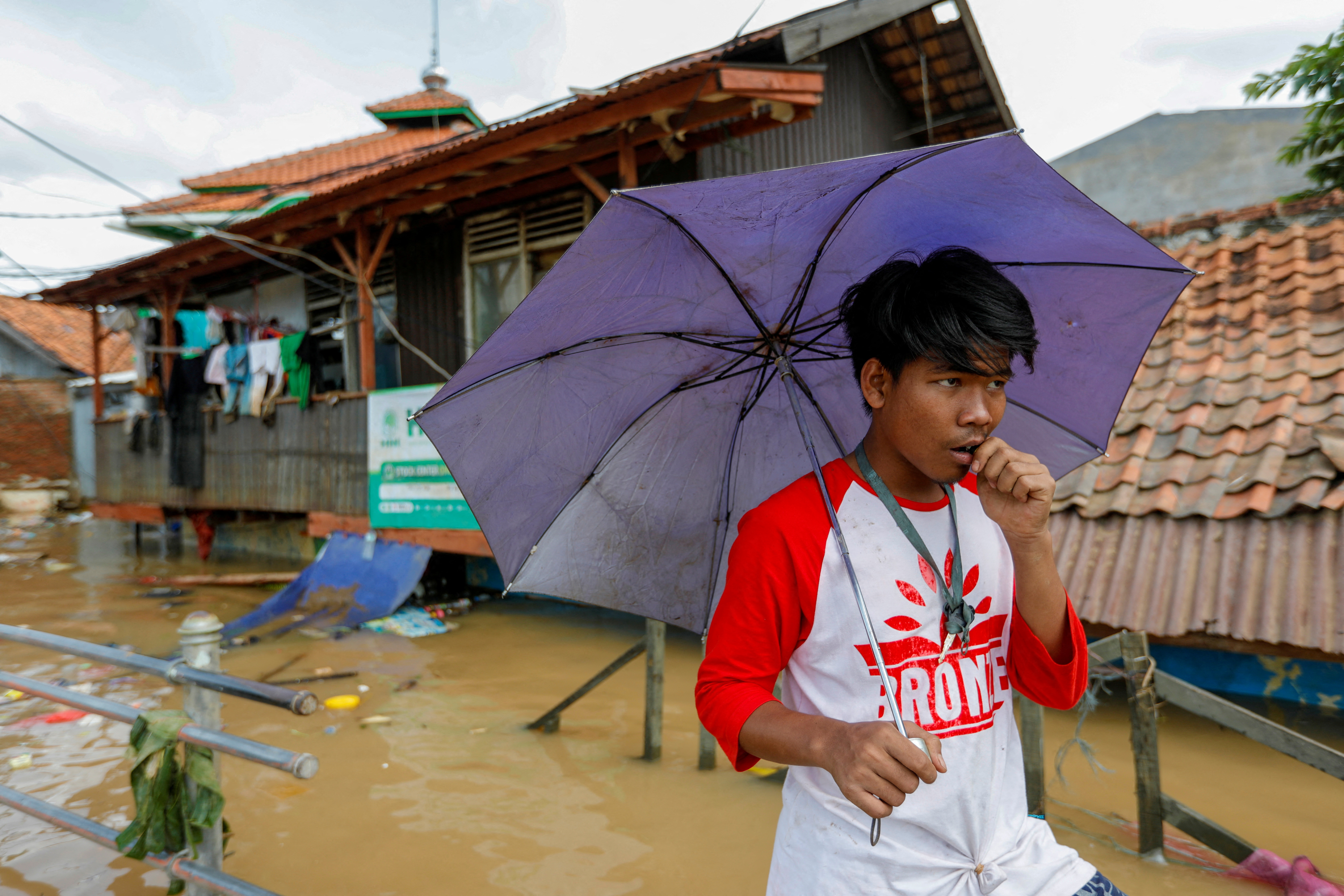 A man holds an umbrella at an area flooded after heavy rains in Jakarta