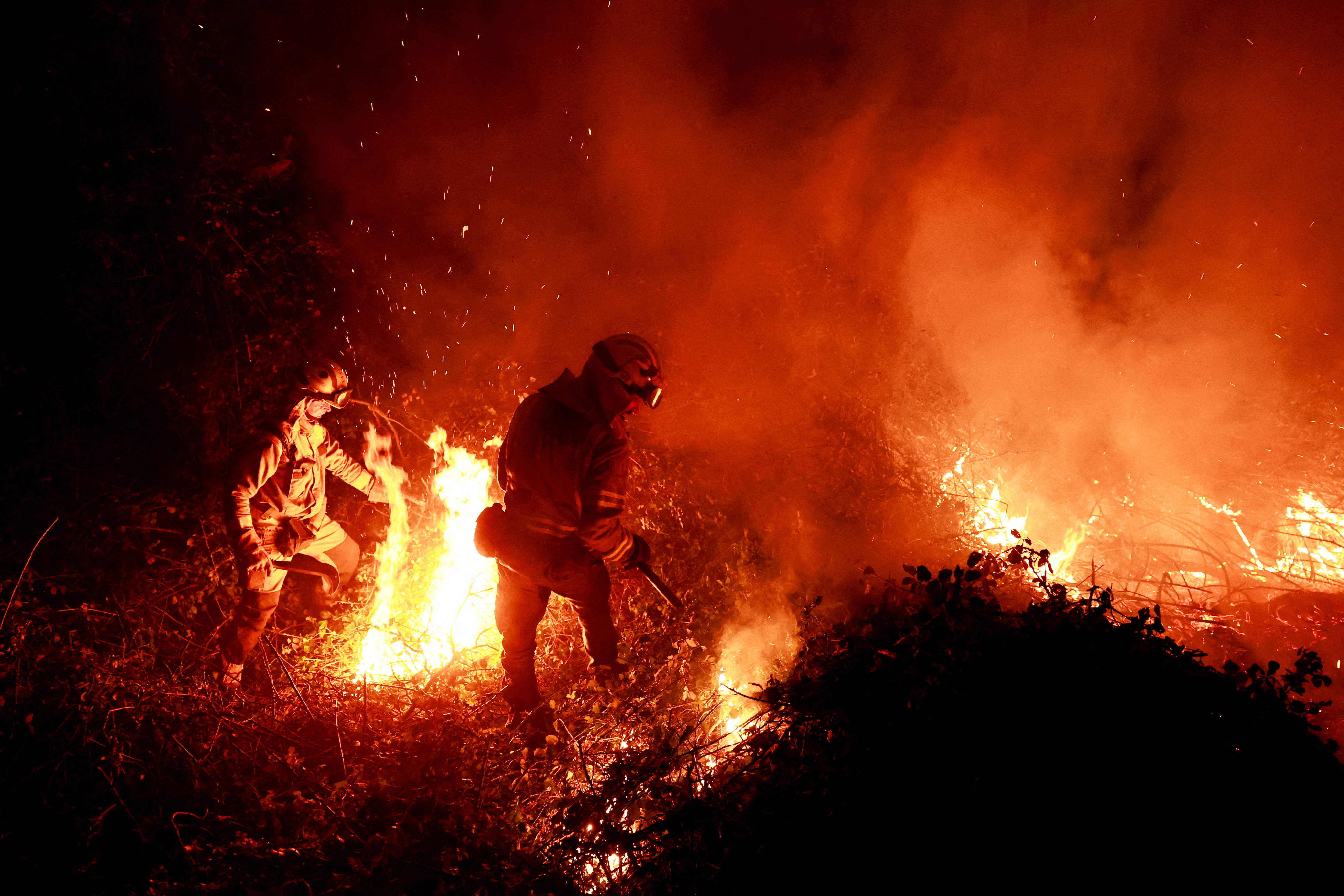 Galician firefighters tackle flames in a forest during an outbreak of forest fires, in Piedrafita