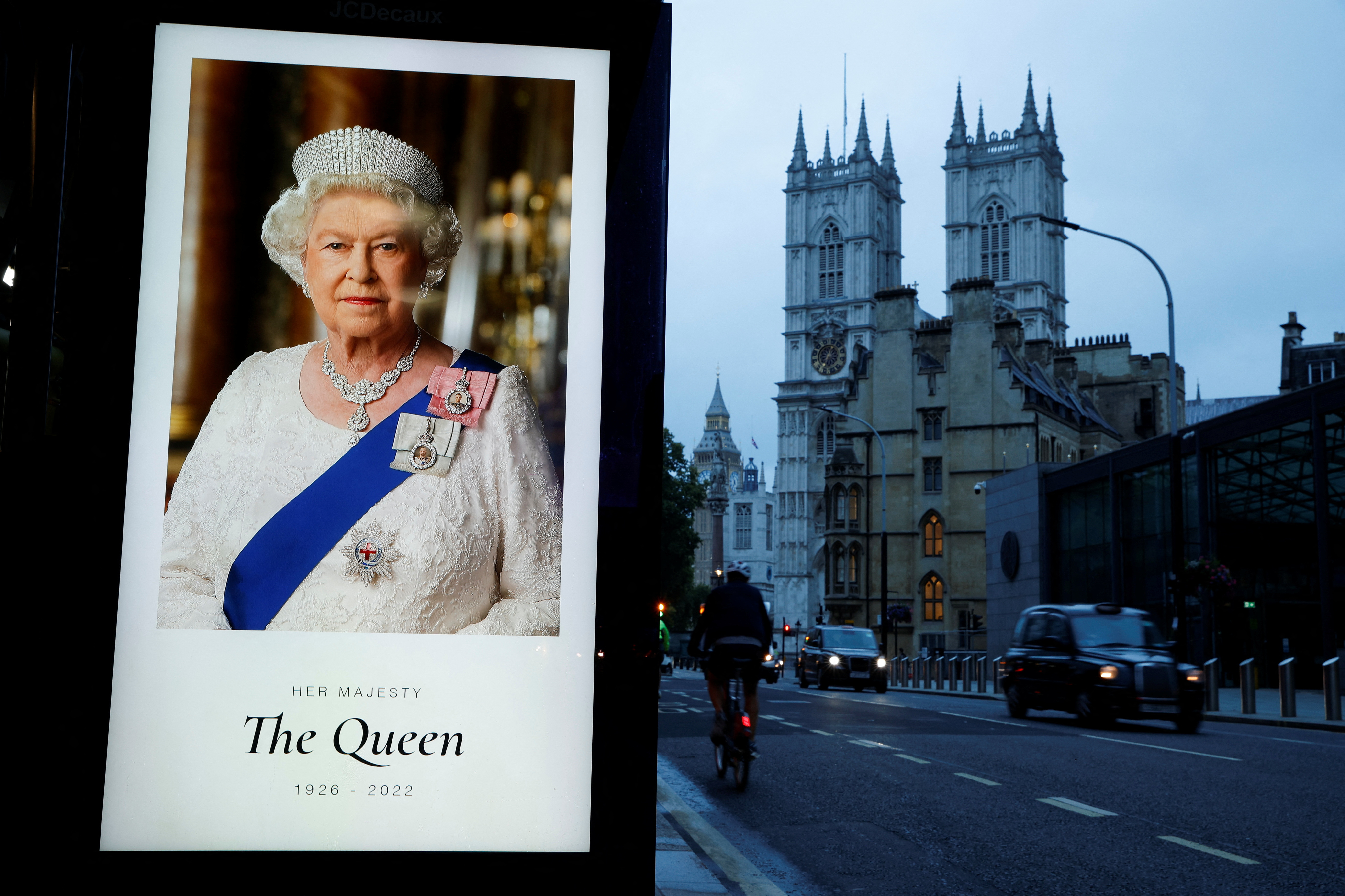 A portrait of Queen Elizabeth is displayed at a bus stand outside Westminster Abbey, in London