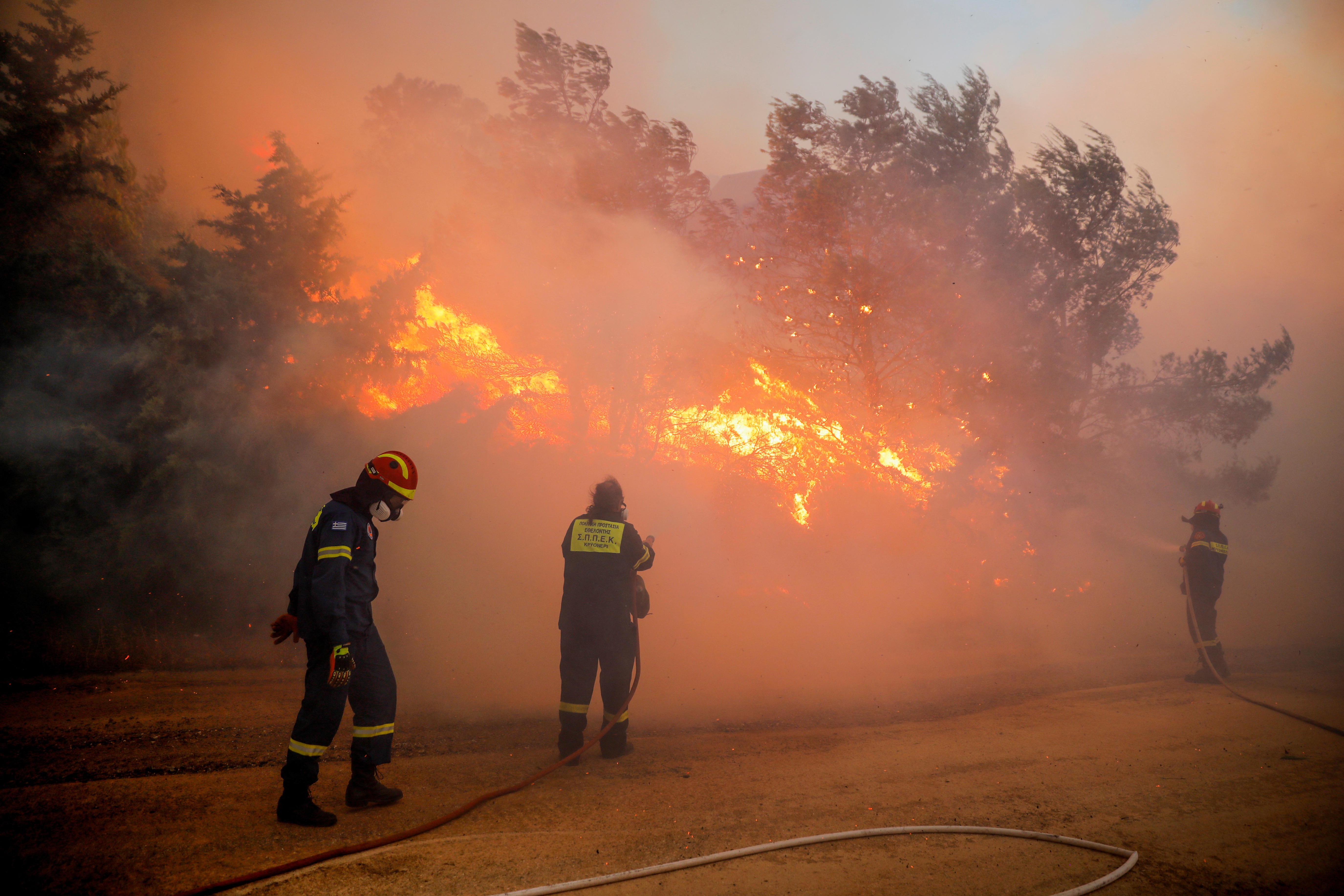 Firefighters try to extinguish a wildfire burning in Ntrafi, Athens