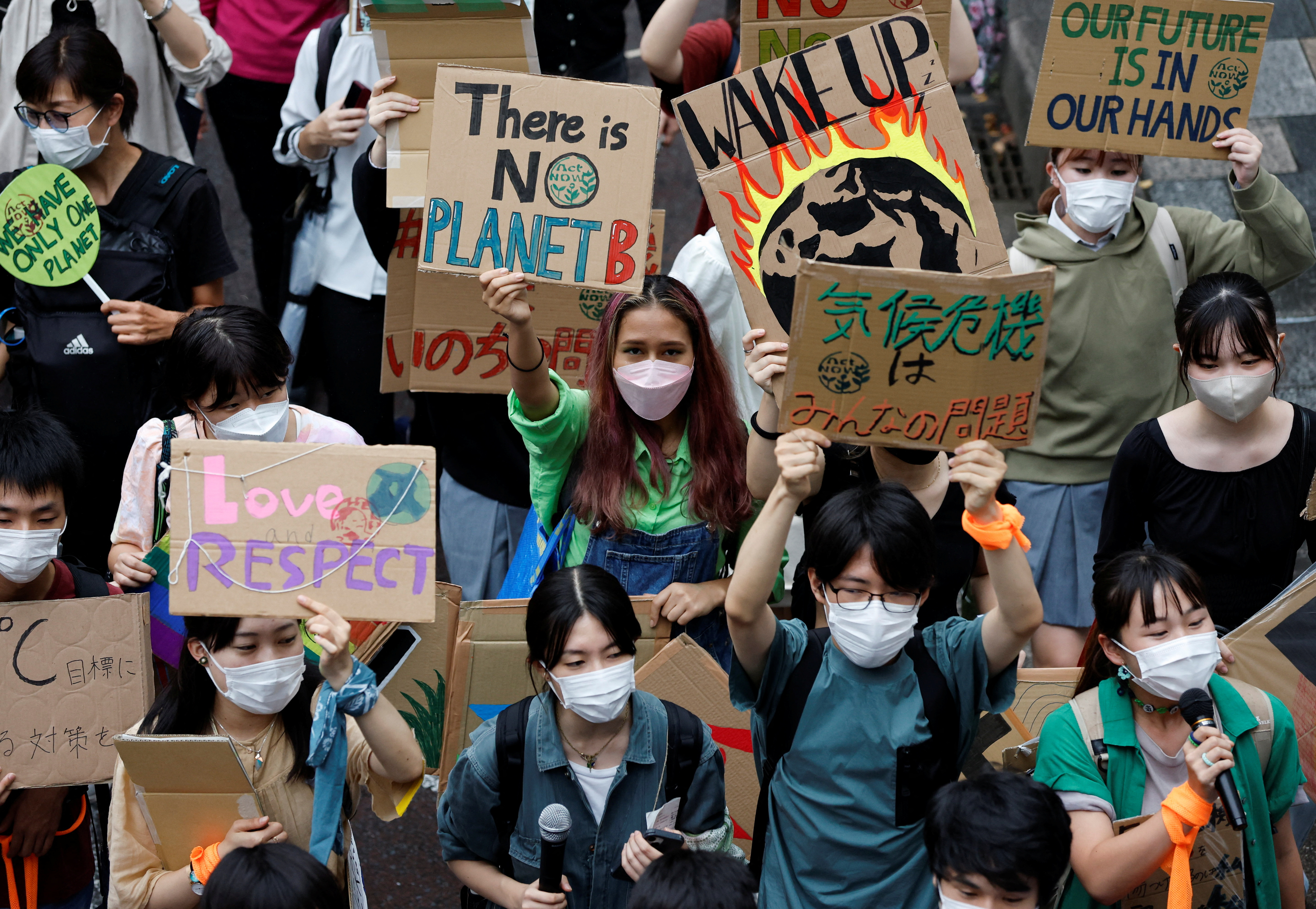 People raise placards as they take part in a global climate protest march, at Omotesando district in Tokyo