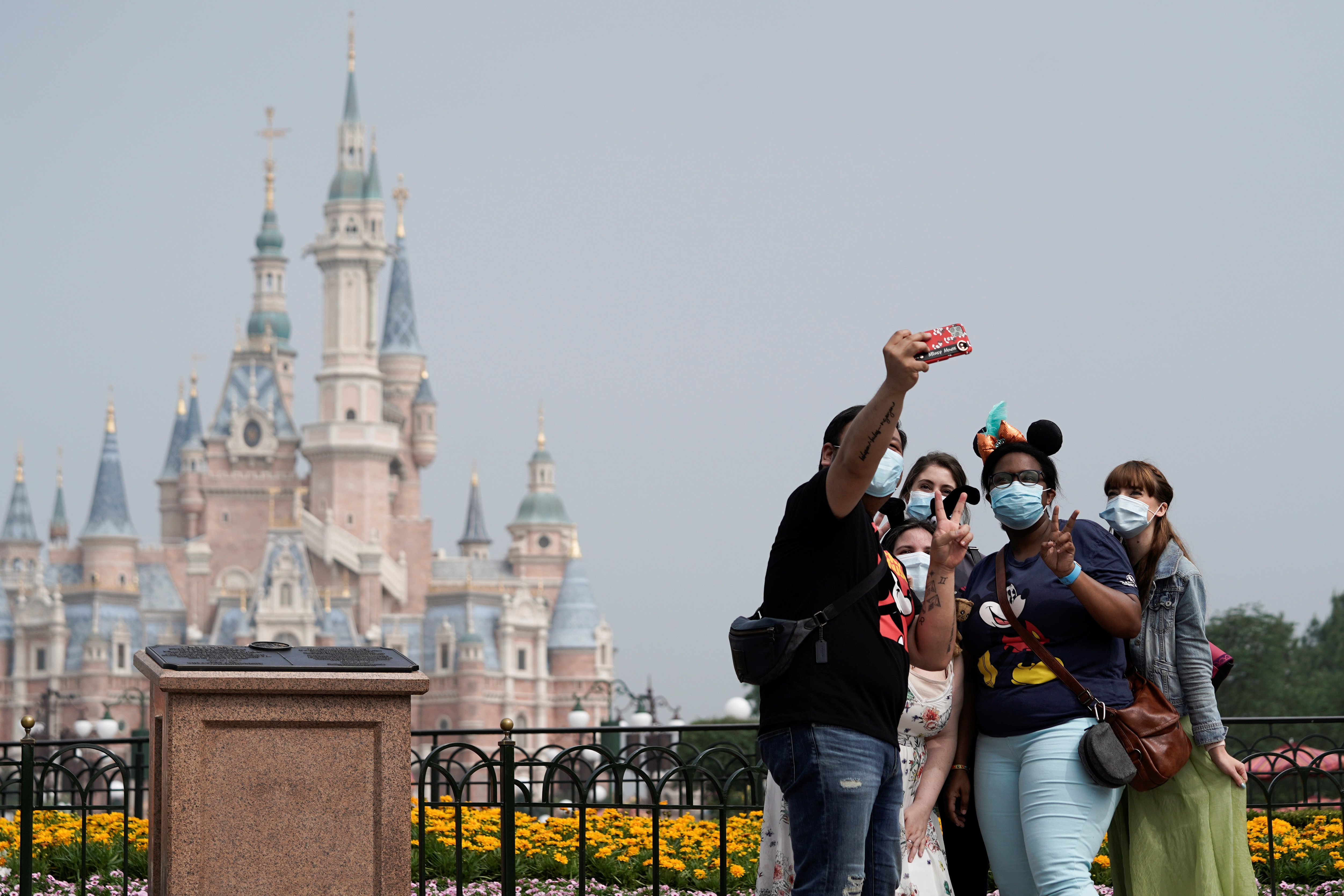 Visitors wearing protective face masks pose for a picture at Shanghai Disney Resort as the Shanghai Disneyland theme park reopens following a shutdown due to the coronavirus disease (COVID-19) outbreak, in Shanghai