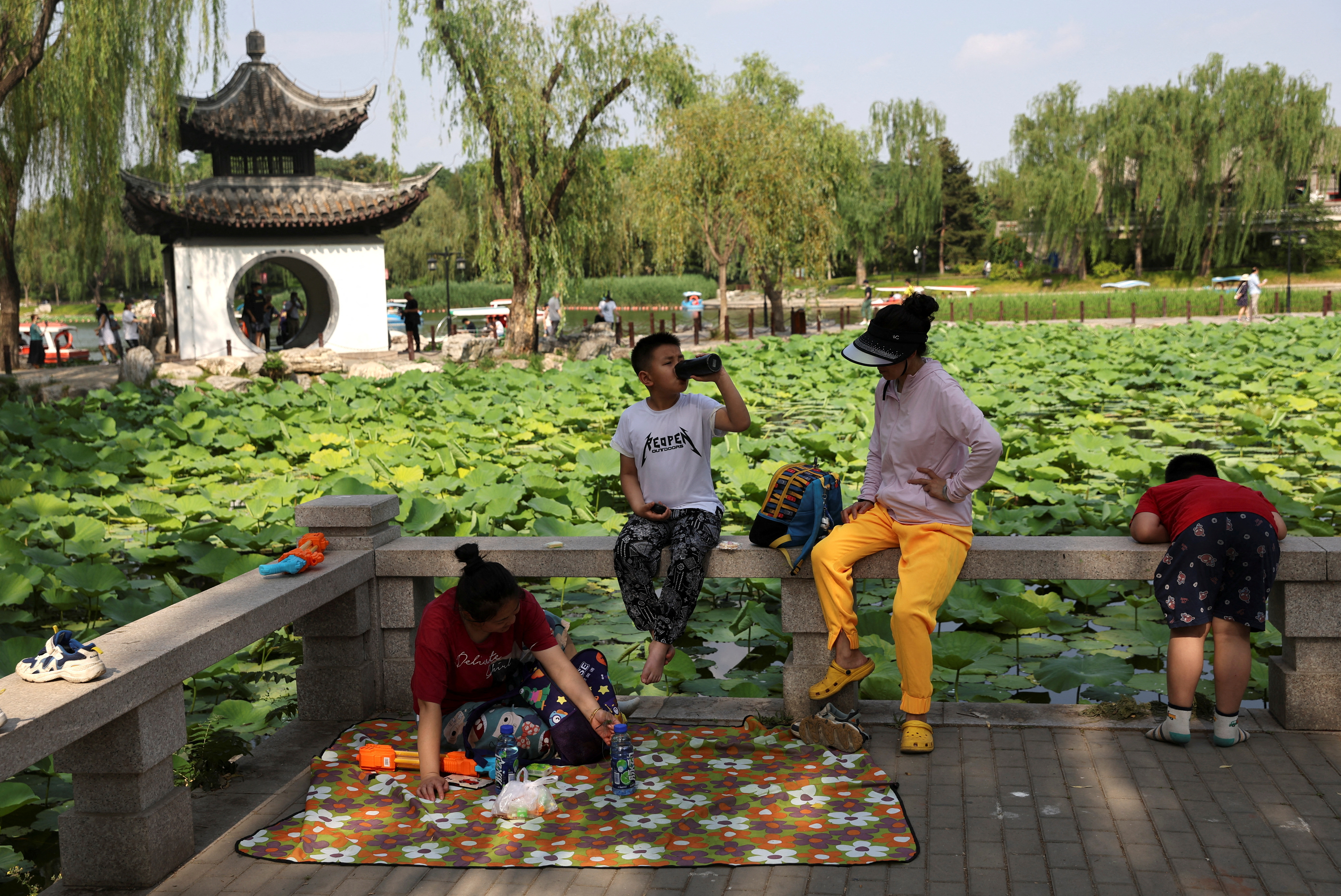 People and children enjoy themselves by the lakeside at a park during the Dragon Boat festival holiday in Beijing
