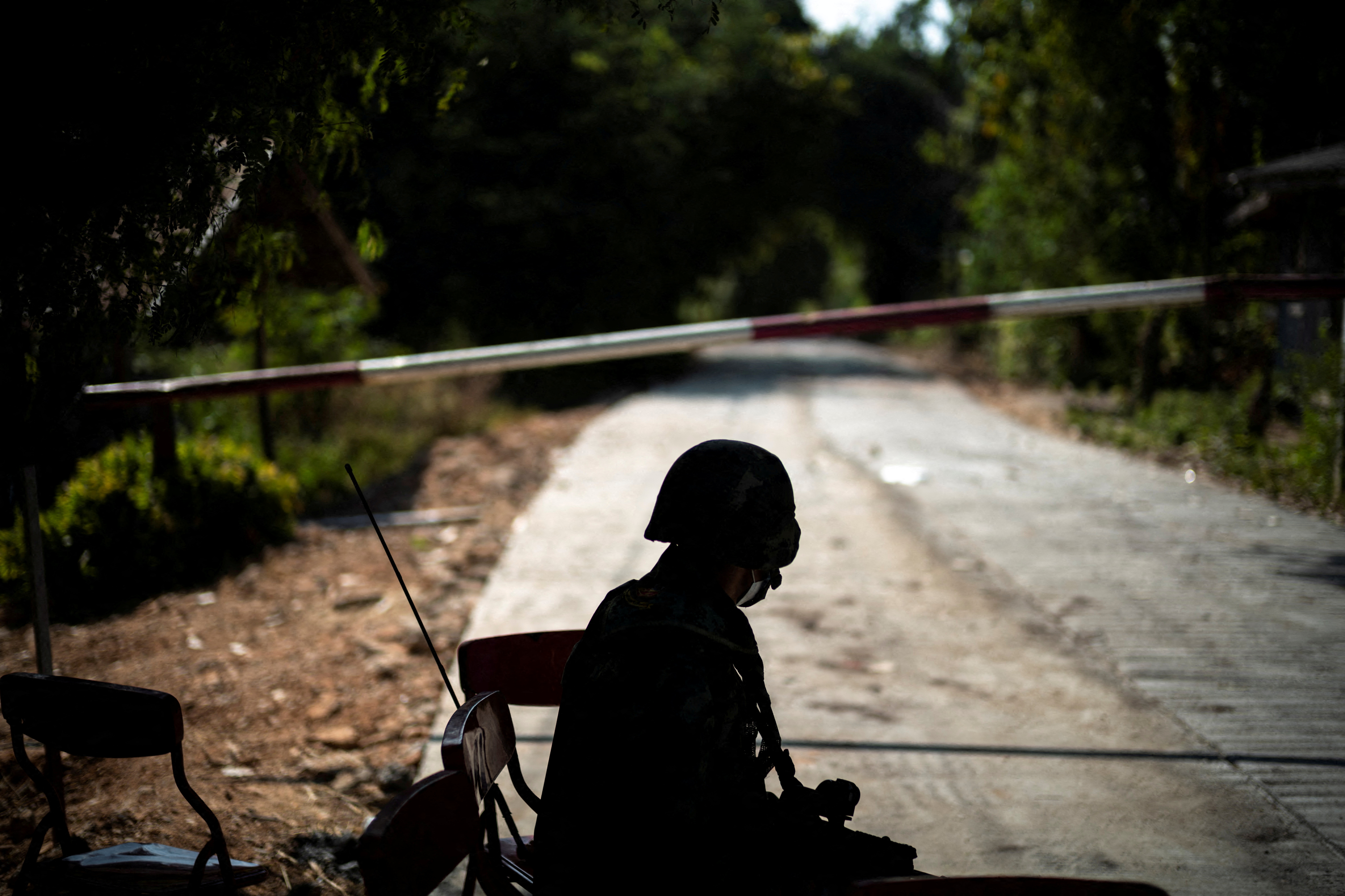 A Thai soldier sits in front of a blocked road leading to the Thailand-Myanmar borde