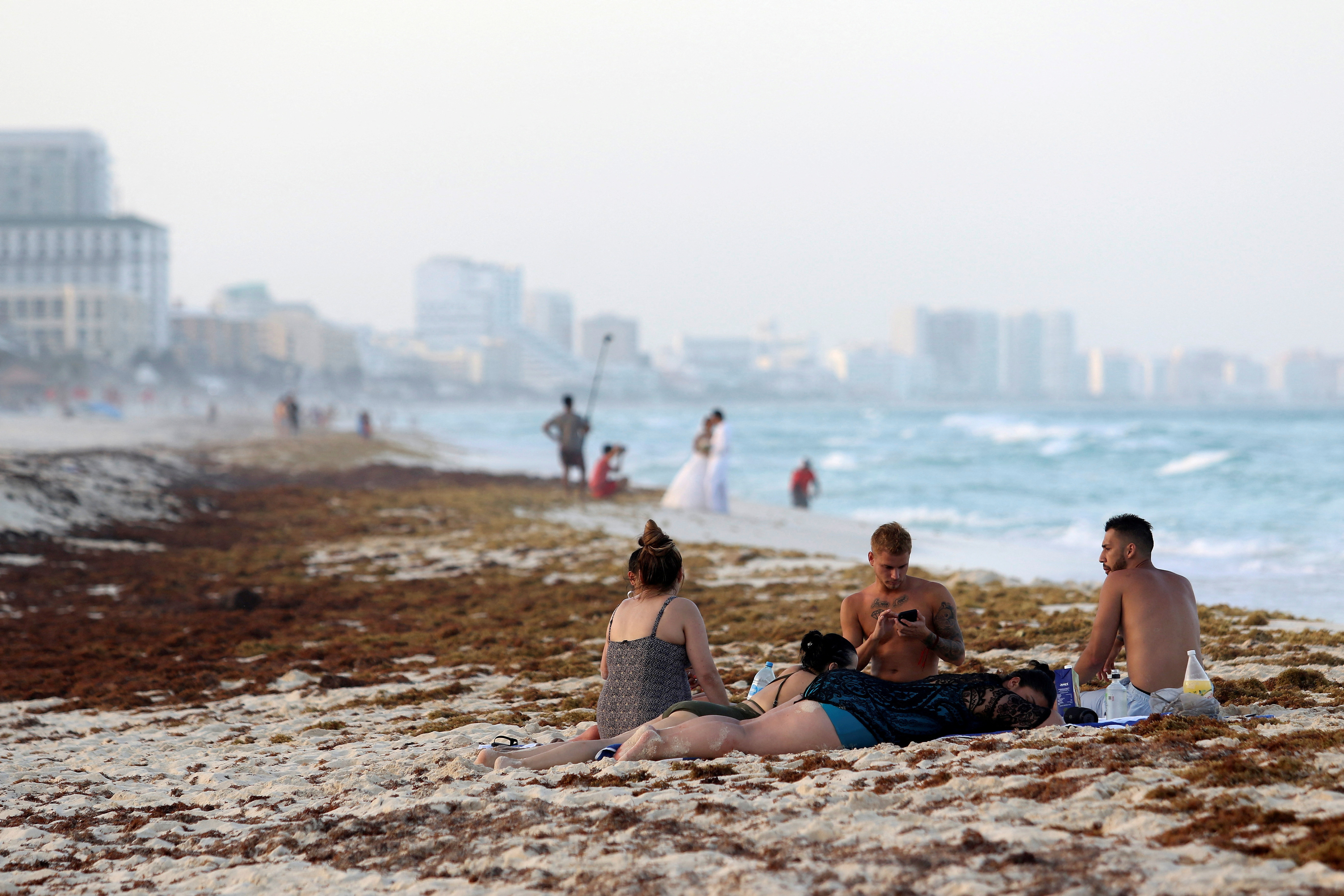 Tourists are seen on a beach covered wth seaweed in Cancun