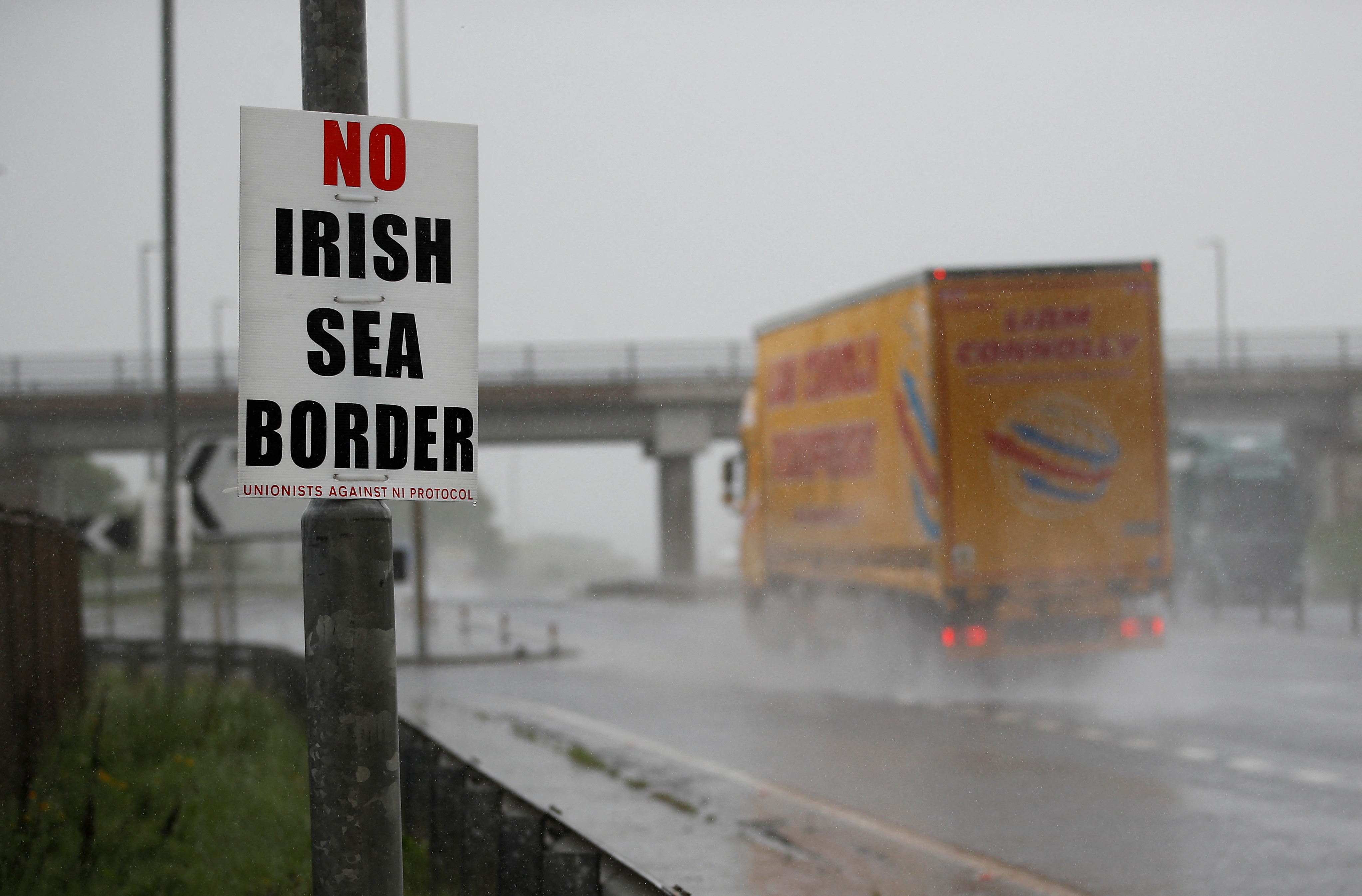 A poster protesting against the Irish sea border is seen next to a road approaching Larne