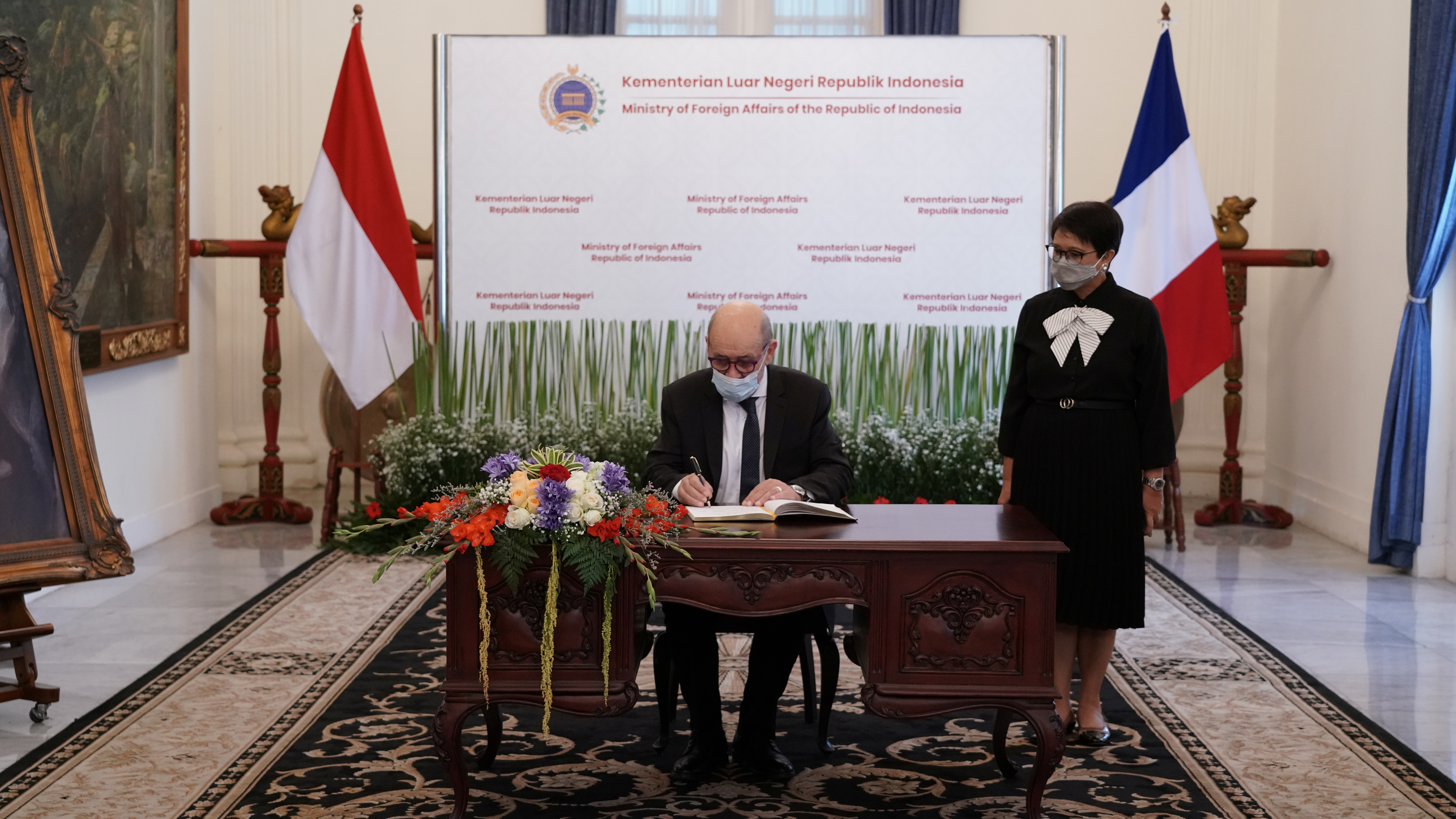 French Foreign Minister Jean-Yves Le Drian signs a guest book as Indonesian Foreign Minister Retno Marsudi watches before their meeting in Jakarta
