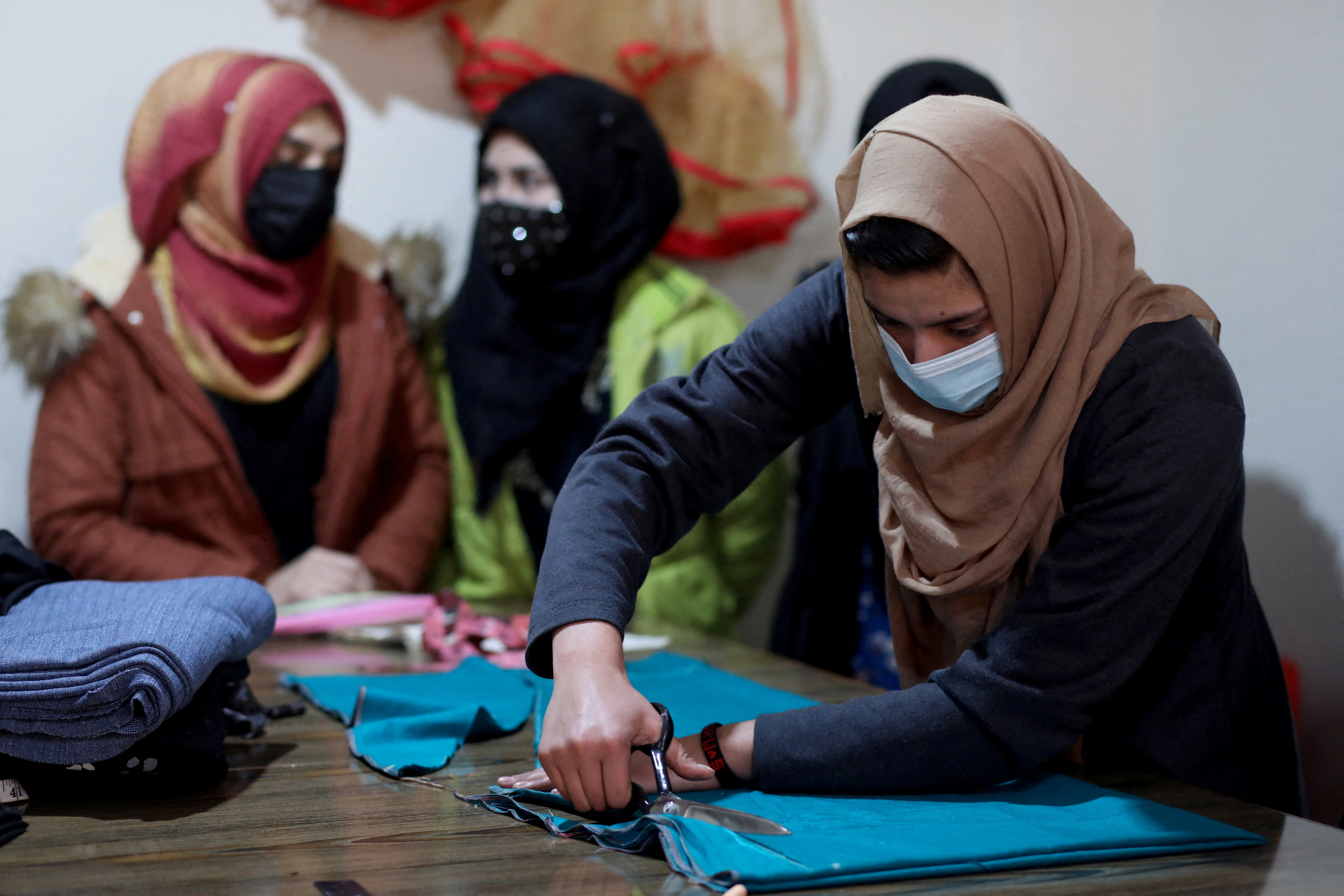 An Afghan woman cuts a fabric at a sewing workshop in Kabul