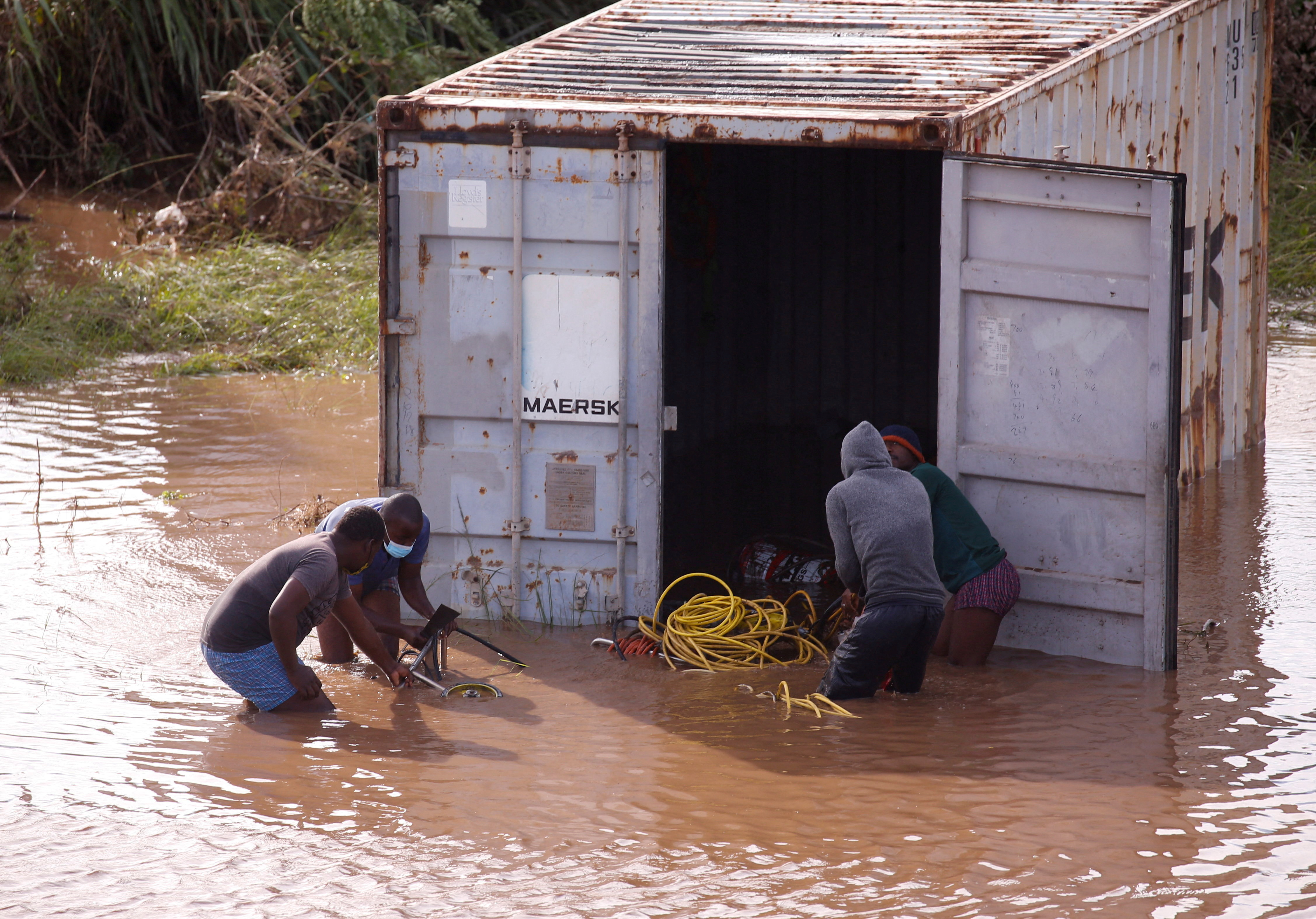 People loot a shipping container which was washed away after heavy rains caused flooding, in Durban